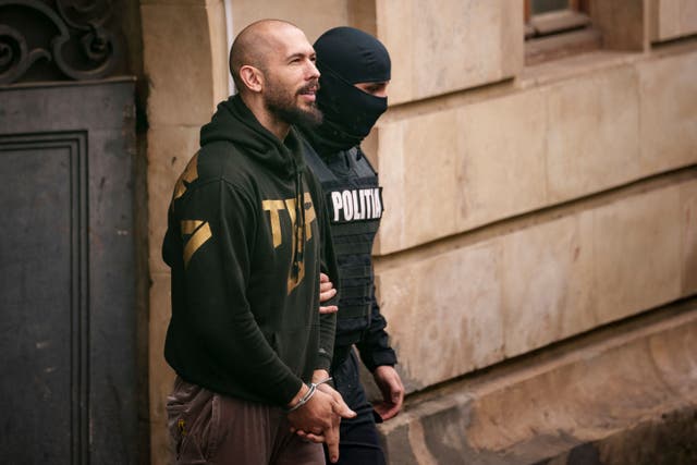 A police officer escorts Andrew Tate from the Court of Appeal in Bucharest (AP Photo/Andreea Alexandru)