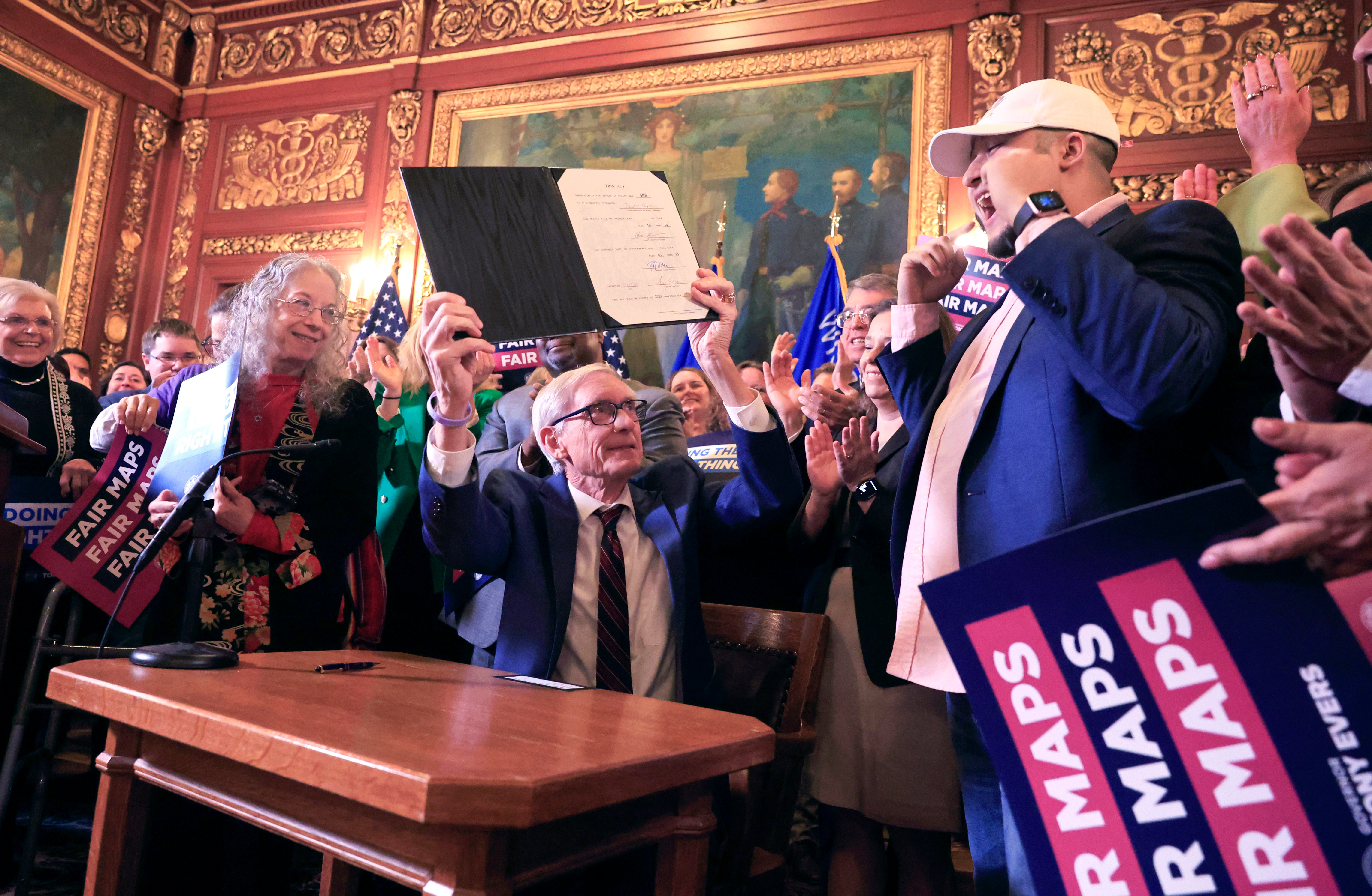 Wisconsin Gov. Tony Evers raises a bill which re-defines the state's legislative maps after signing it at the Wisconsin State Capitol in Madison, Wis., on Monday, Feb. 19, 2024
