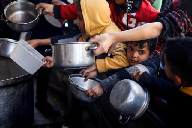 <p>Palestinian children wait to receive food cooked by a charity kitchen amid shortages of supplies in Rafah</p>
