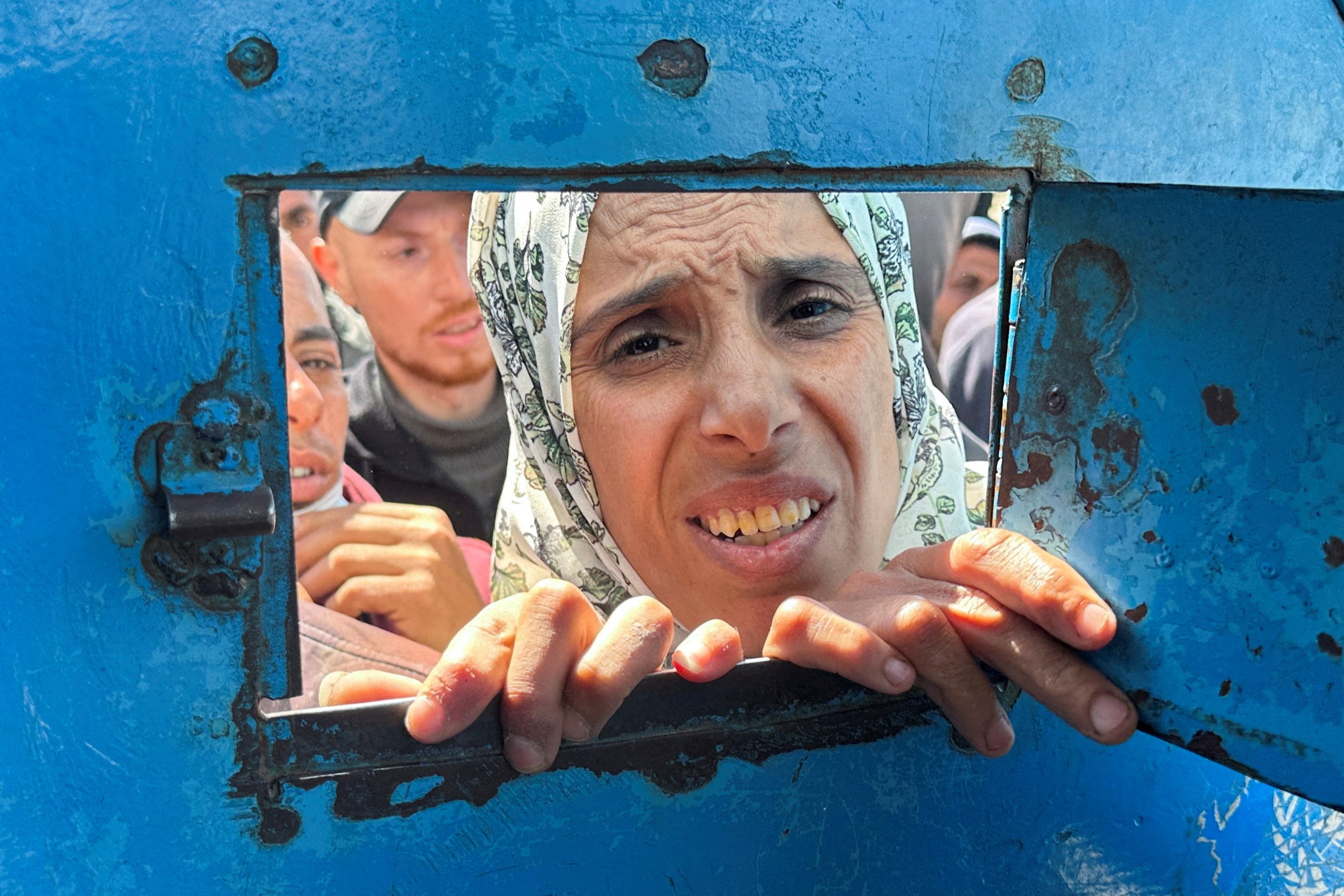A Palestinian woman waits to receive aid from a UNRWA distribution in Rafah