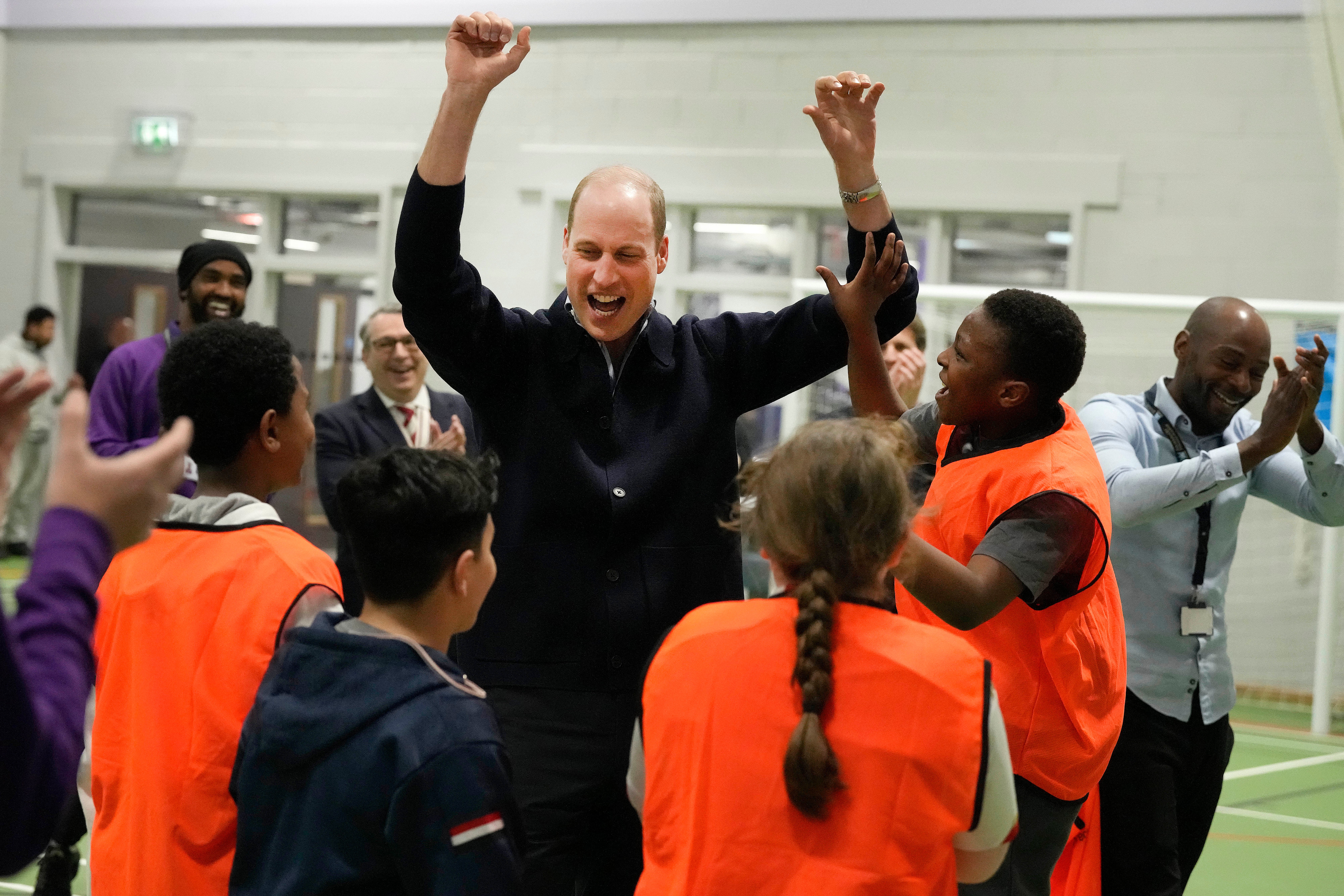 The Prince of Wales celebrates with young people after he threw a basket, during a visit to WEST, the new OnSide charity youth zone in Hammersmith and Fulham