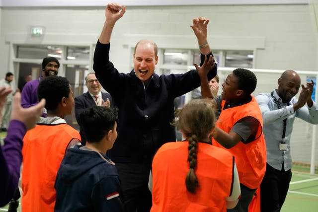<p>The Prince of Wales celebrates with young people after he threw a basket, during a visit to WEST, the new OnSide charity youth zone in Hammersmith and Fulham</p>