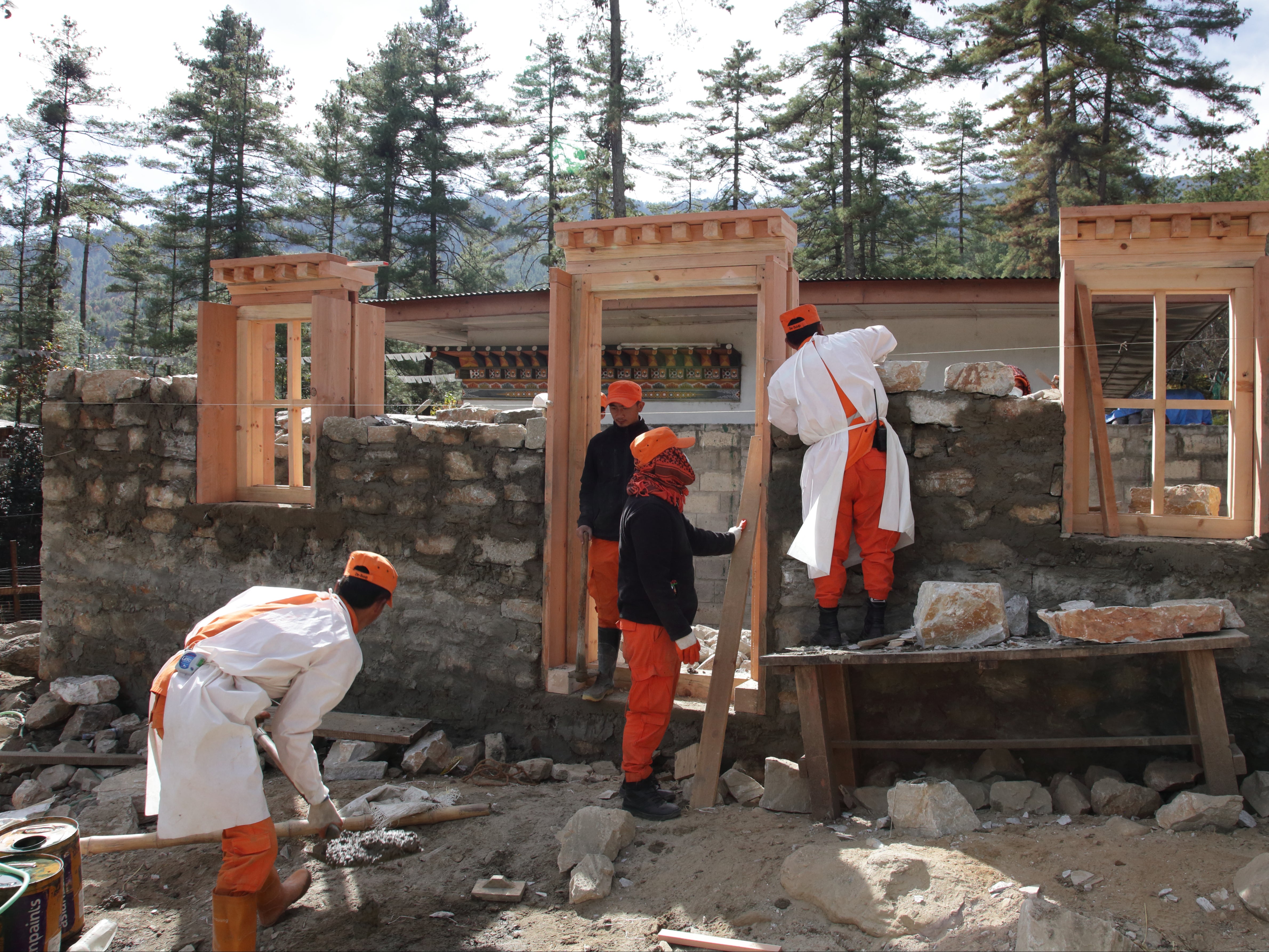 Bhutanese volunteers, always in orange, helping on a building project