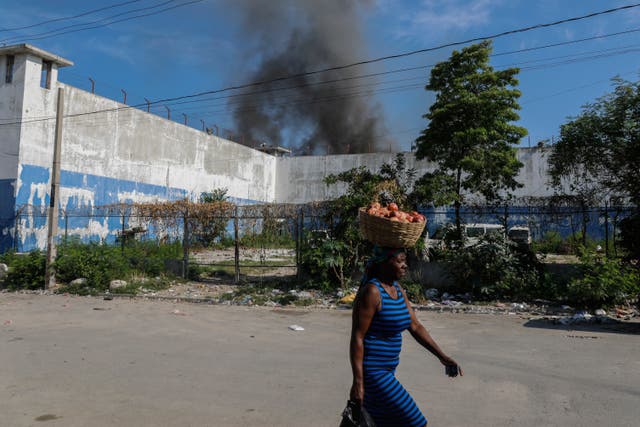 <p>A woman walks past the smoking, empty National Penitentiary after a small fire broke out inside the jail in downtown Port-au-Prince, Haiti, Haiti, on 14 March 2024</p>