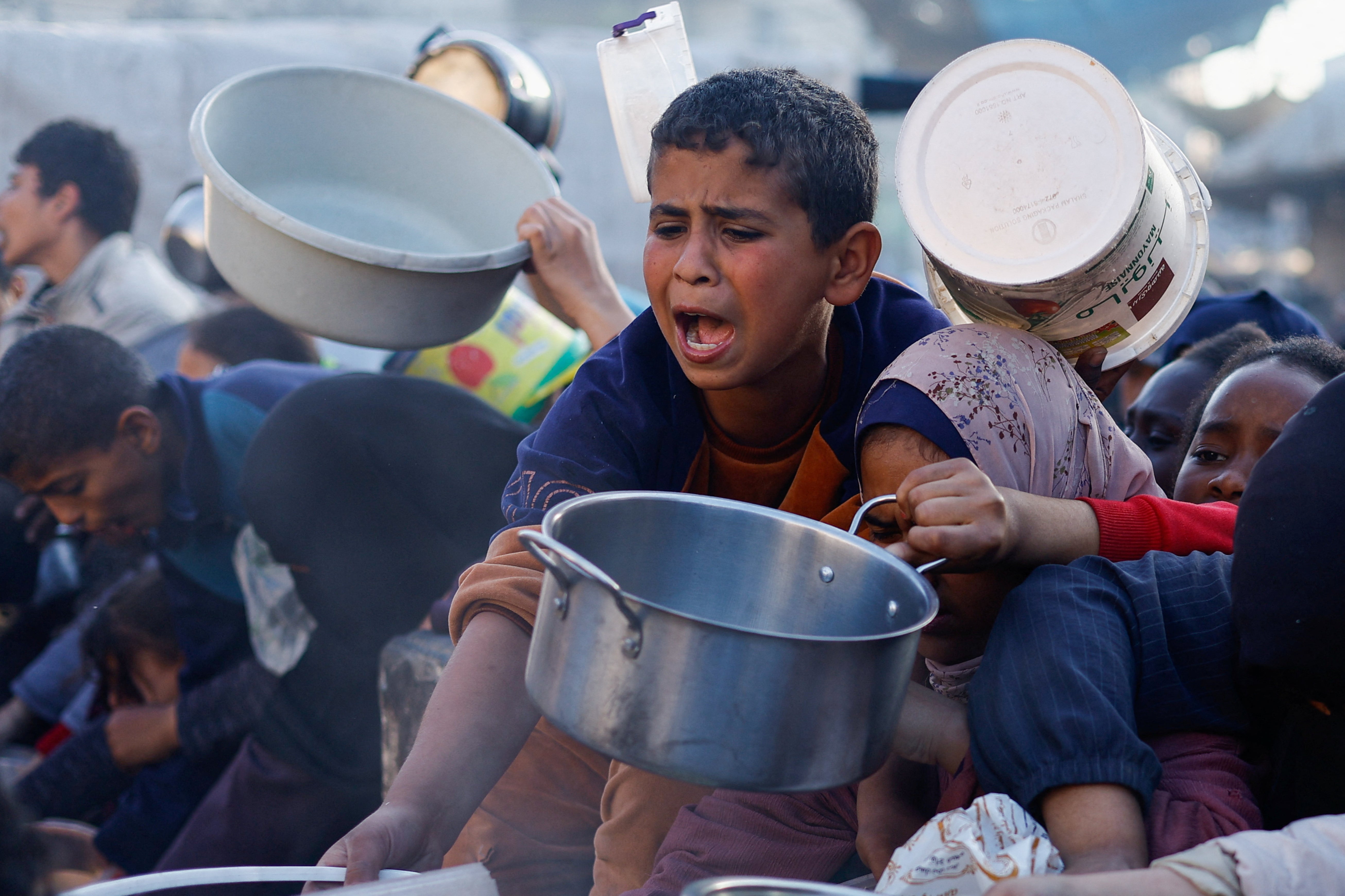Palestinian children wait to receive food in Rafah