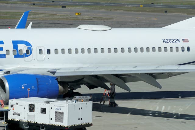 <p>A Medford Jet Center worker walks under a United Boeing 737-824 that landed at Rogue Valley International-Medford Airport from San Francisco with a missing panel on 15 March 2024</p>