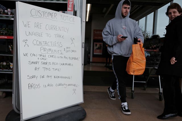 A handwritten sign outside a Sainsbury’s store in Cobham informs customers of technical issues (Yui Mok/PA)