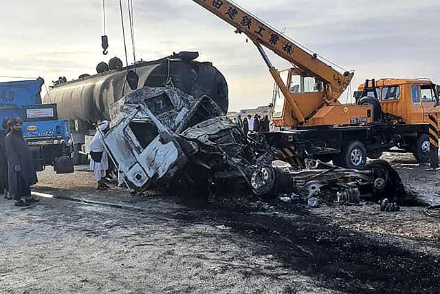 <p>Security personnel and volunteers standing near the wreckage of burned passenger bus and oil tanker on the Herat-Kandahar highway in Grishk district of Helmand province</p>