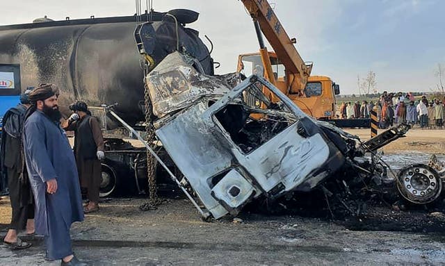 <p>File This handout photograph released by Afghanistan's Helmand Information Department on March 17, 2024 shows security personnel and volunteers standing near the wreckage of burned passenger bus and oil tanker after they and a motorbike collided on the Herat-Kandahar highway in Grishk district of Helmand province</p>