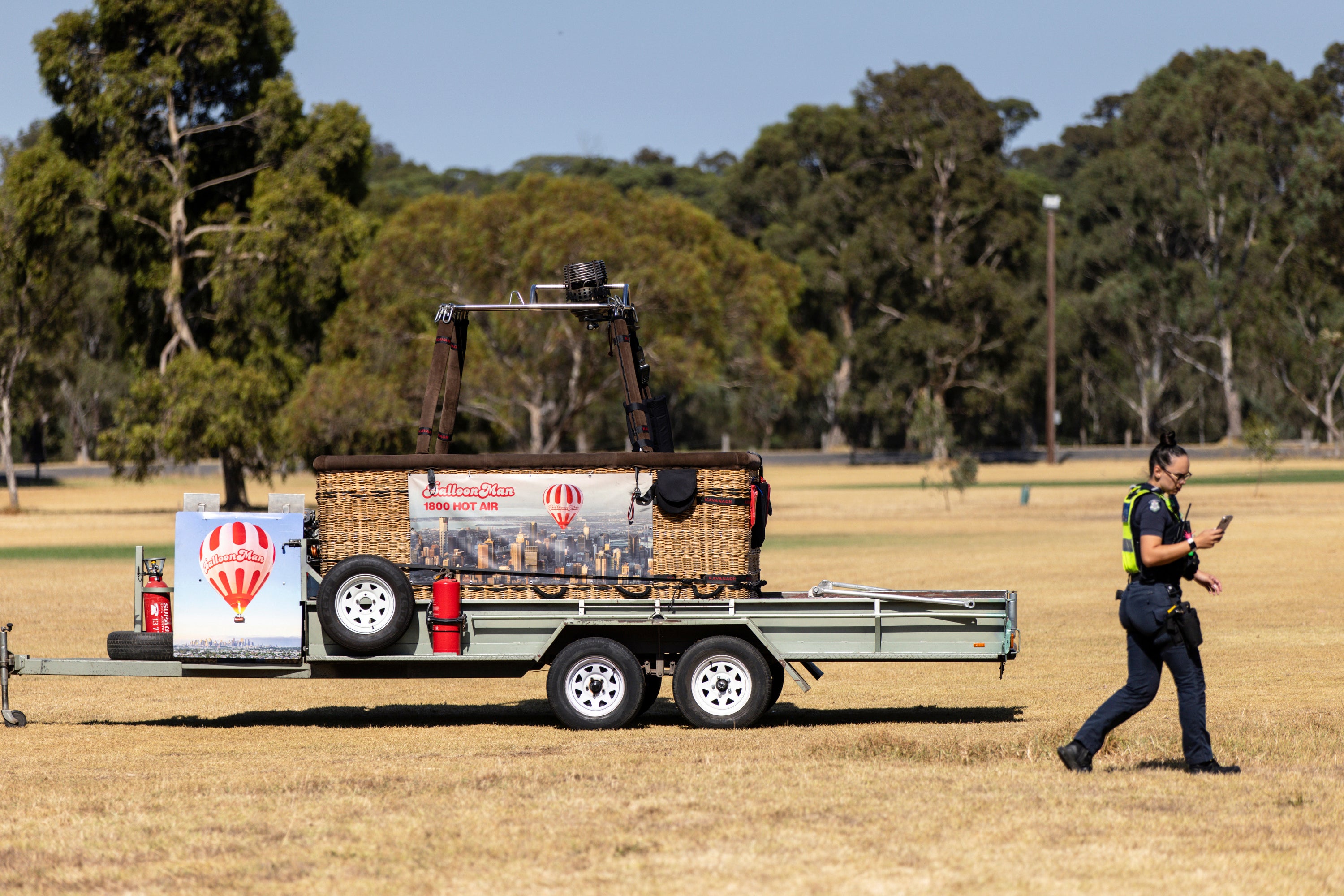 A police officer walks past a trailer with a hot-air balloon basket on it after the discovery of a man's body at Yarra Bend Park in Melbourne, Monday, 18 March 2024