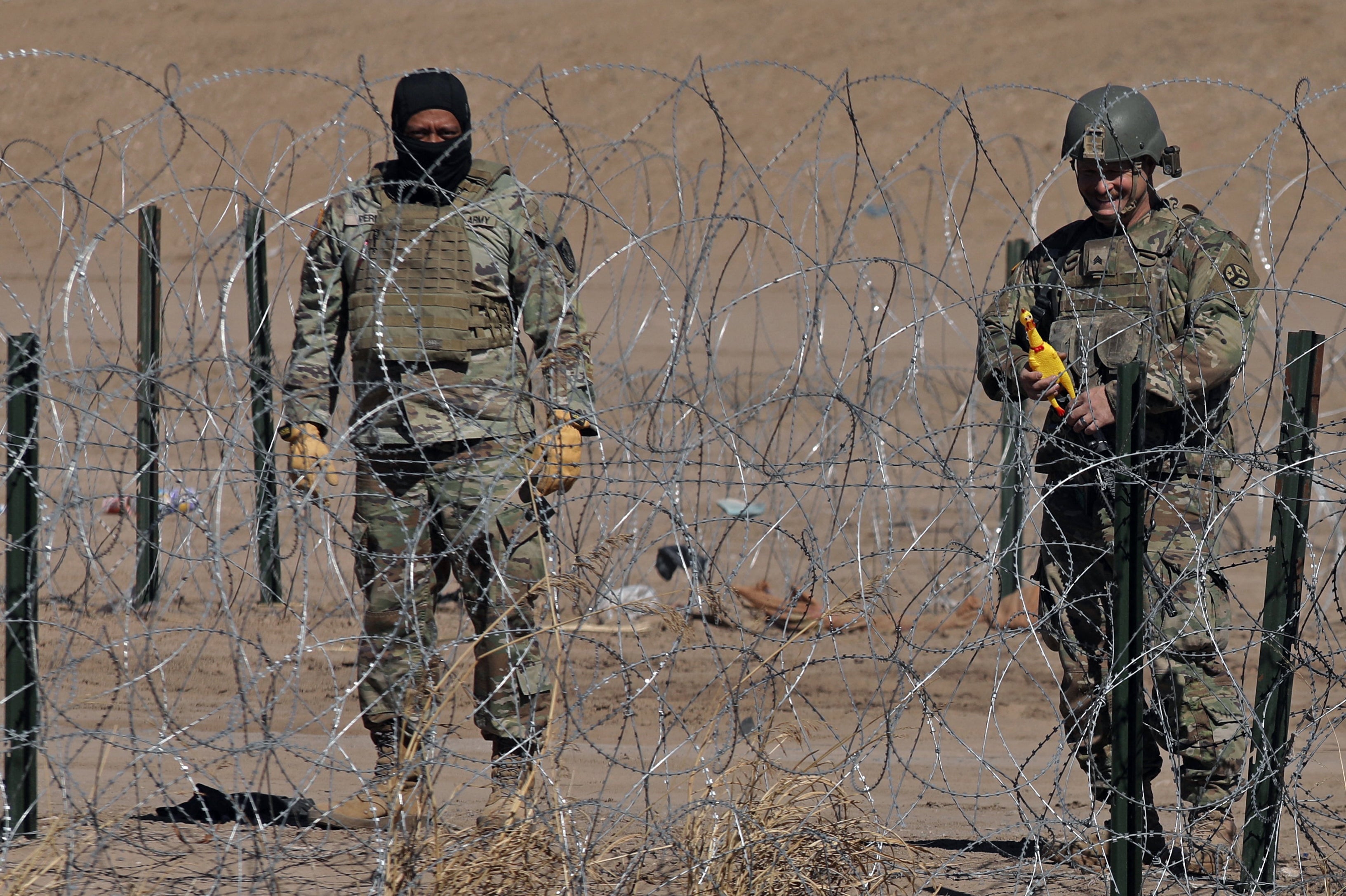 A Texas National Guard agent near a barbed wire fence installed to prevent the entry of migrants across the Rio Bravo/Grande from Ciudad Juarez