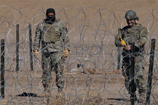 <p>A Texas National Guard agent plays with a toy rubber chicken that makes sounds, in front of an immigrant, near a barbed wire fence installed to prevent the entry of illegal migrants across the Rio Bravo/Grande from Ciudad Juarez, state of Chihuahua, Mexico on February 12, 2024. (</p>