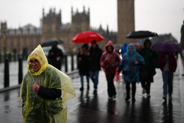 <p>Tourists shelter from the rain as they walk over Westminster Bridge, with the Houses of Parliament in the background, in London on March 10, 2024. (Photo by HENRY NICHOLLS / AFP) (Photo by HENRY NICHOLLS/AFP via Getty Images)</p>