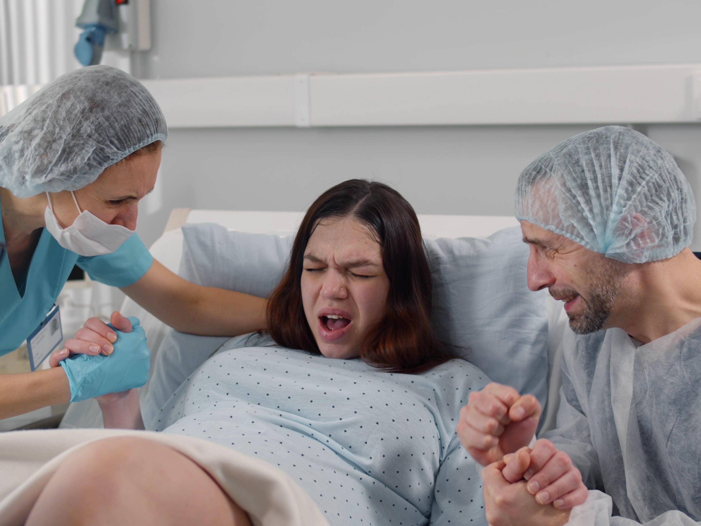 <p>Husband and nurses supporting pregnant woman hardly breathing during child birth. </p>