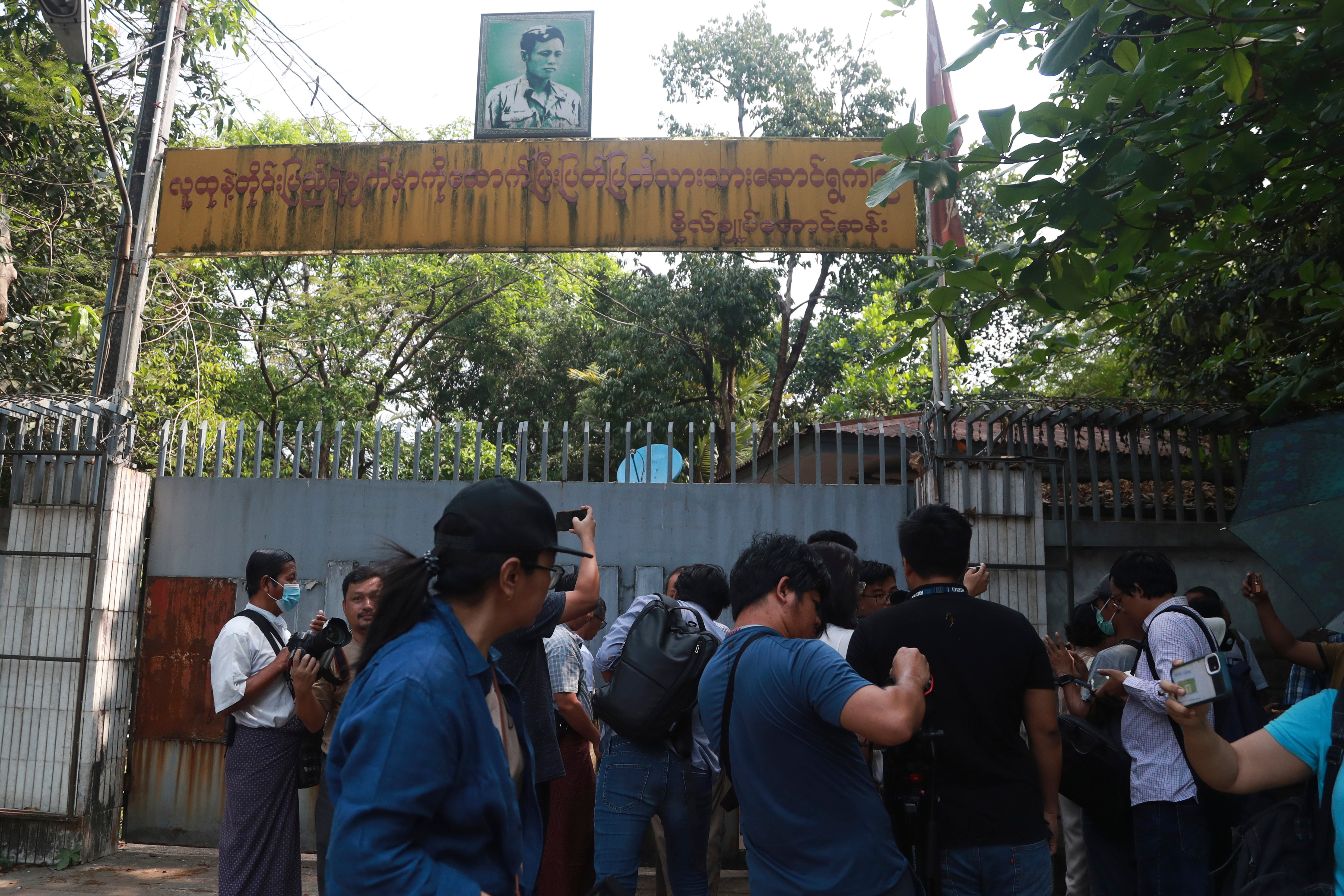 Journalists gather during an auction outside the residence of ousted leader Aung San Suu Kyi in Yangon