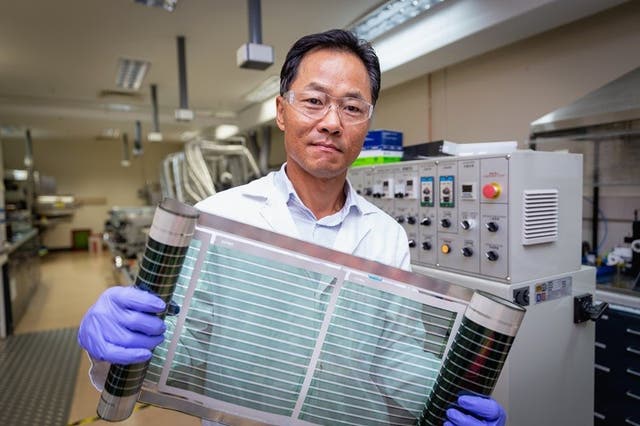 <p>Dr Doojin Vak holds up a roll of flexible printed solar cells that use the ‘miracle material’ perovskite</p>