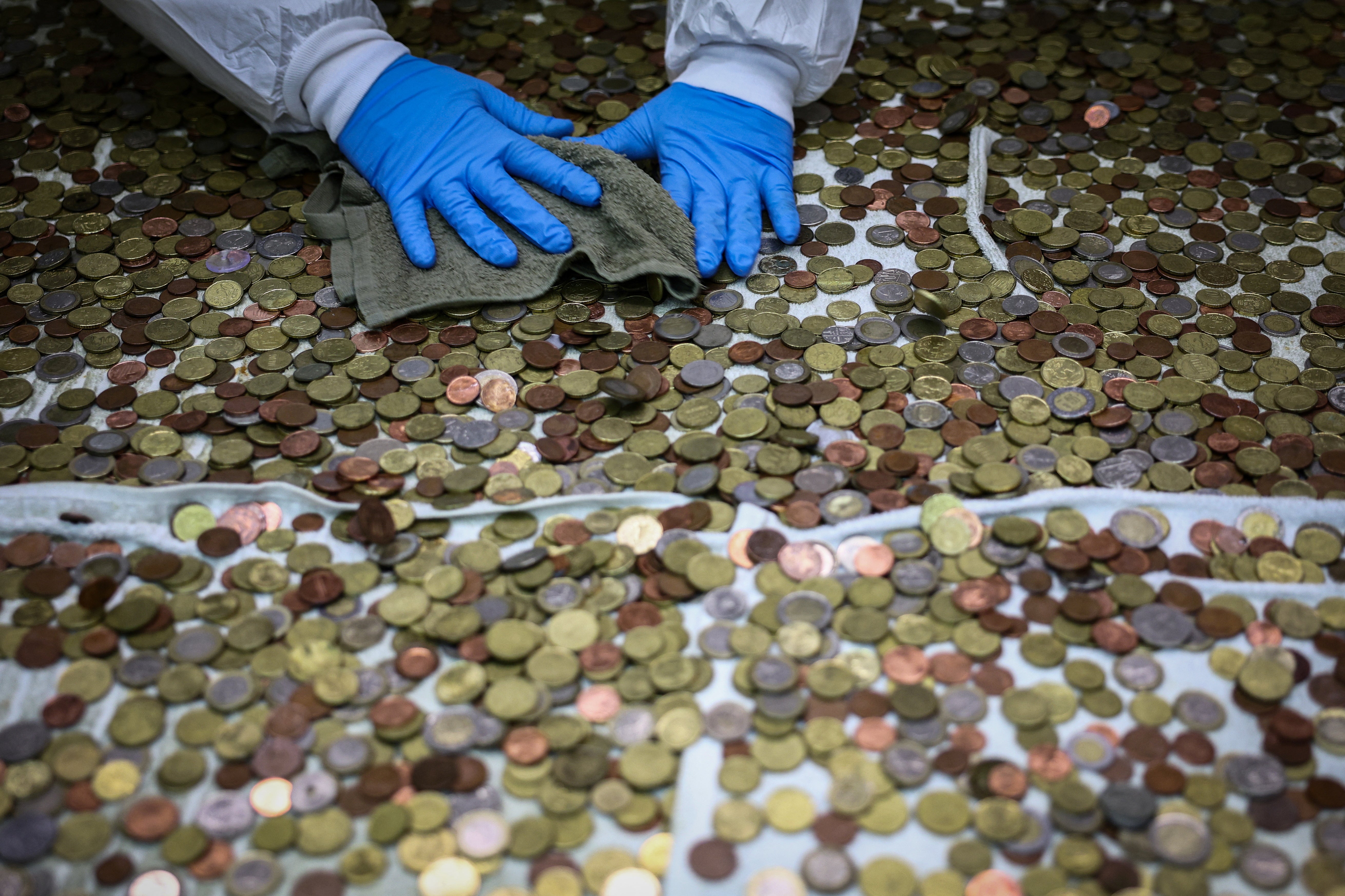 Caritas worker Fabrizio Marchioni, 52, dries coins collected from the fountain
