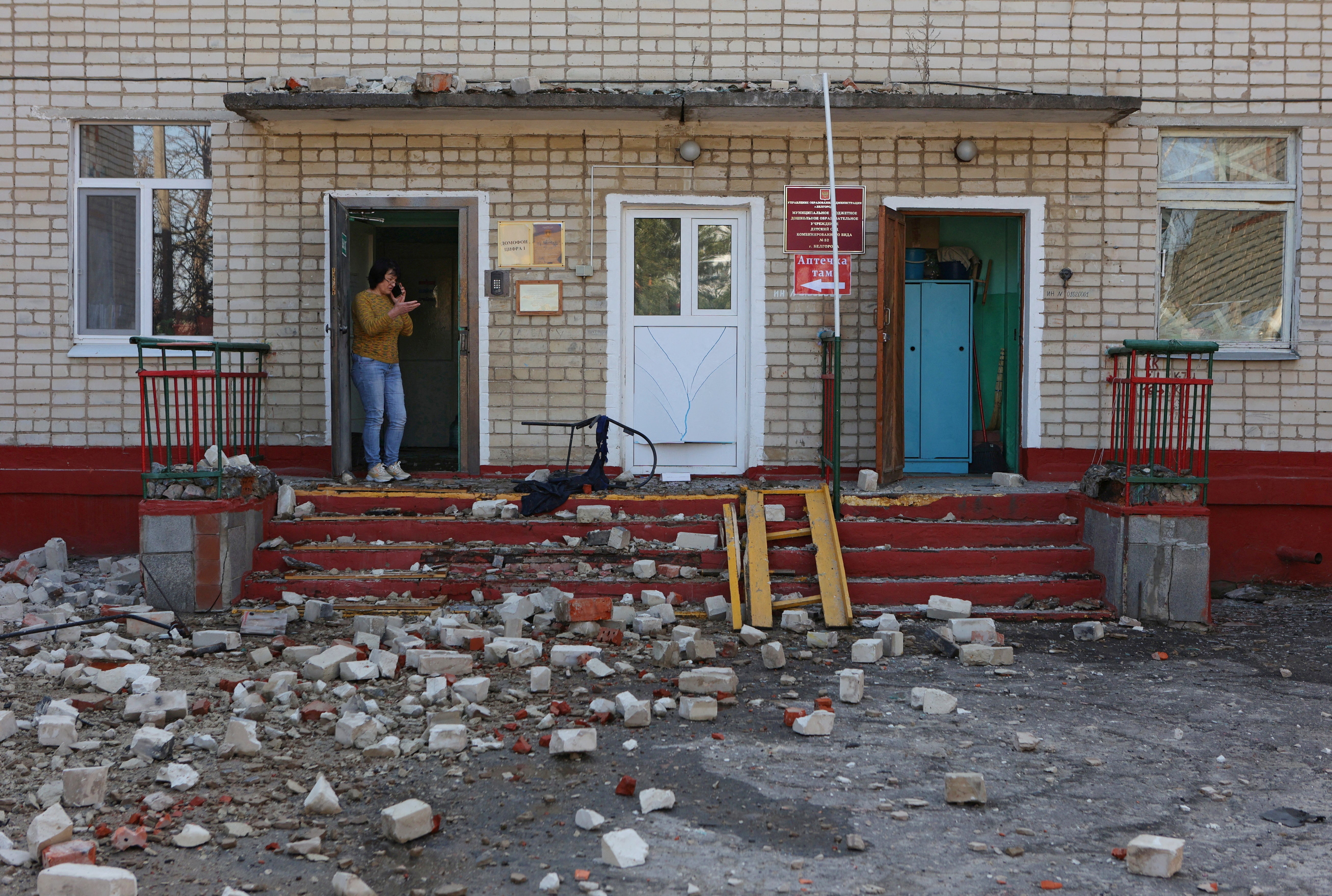 A woman stands at the entrance to a kindergarten building hit by shelling, what local authorities called a Ukrainian military strike