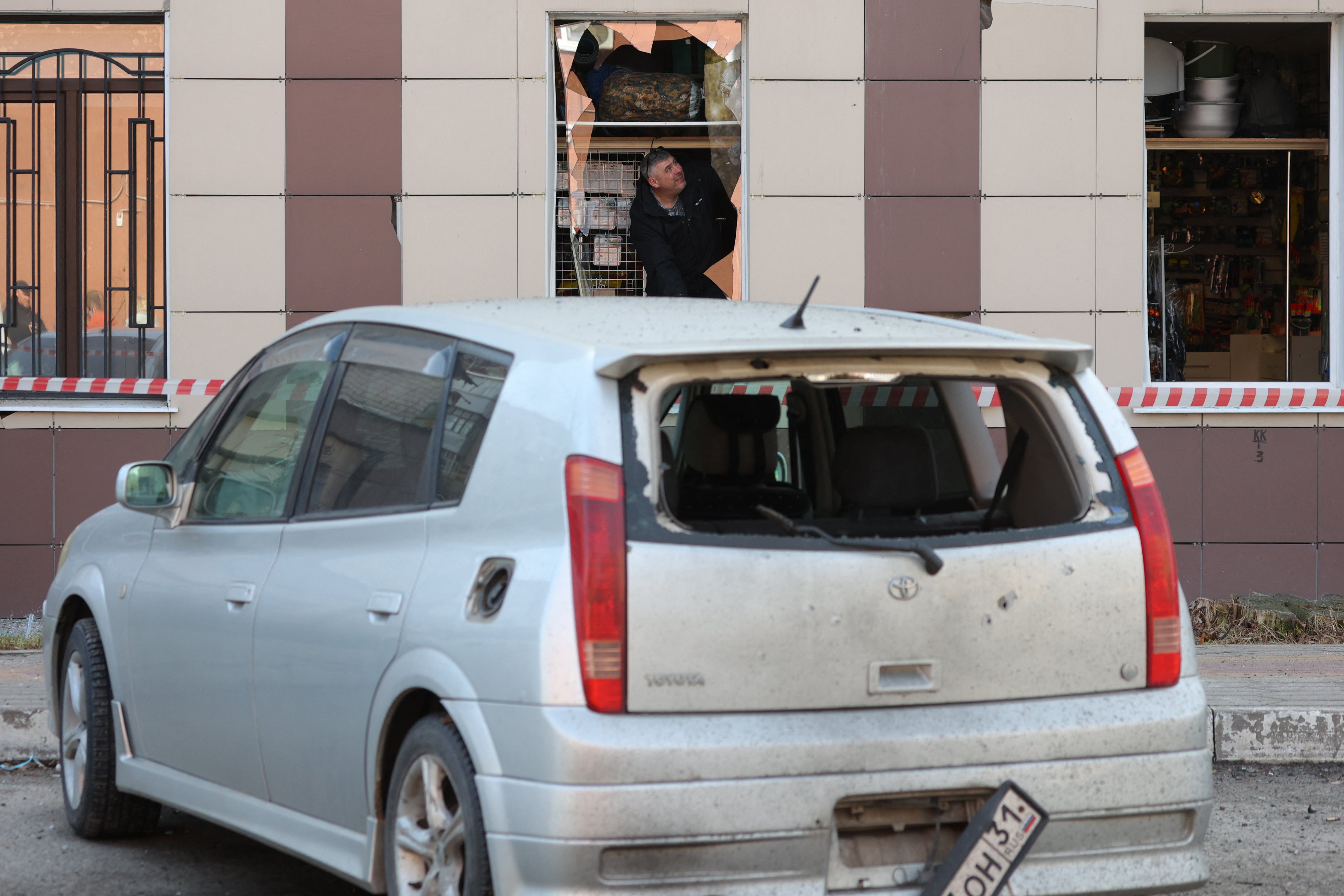 A man inspects damage to a shop following fresh aerial attacks in Belgorod