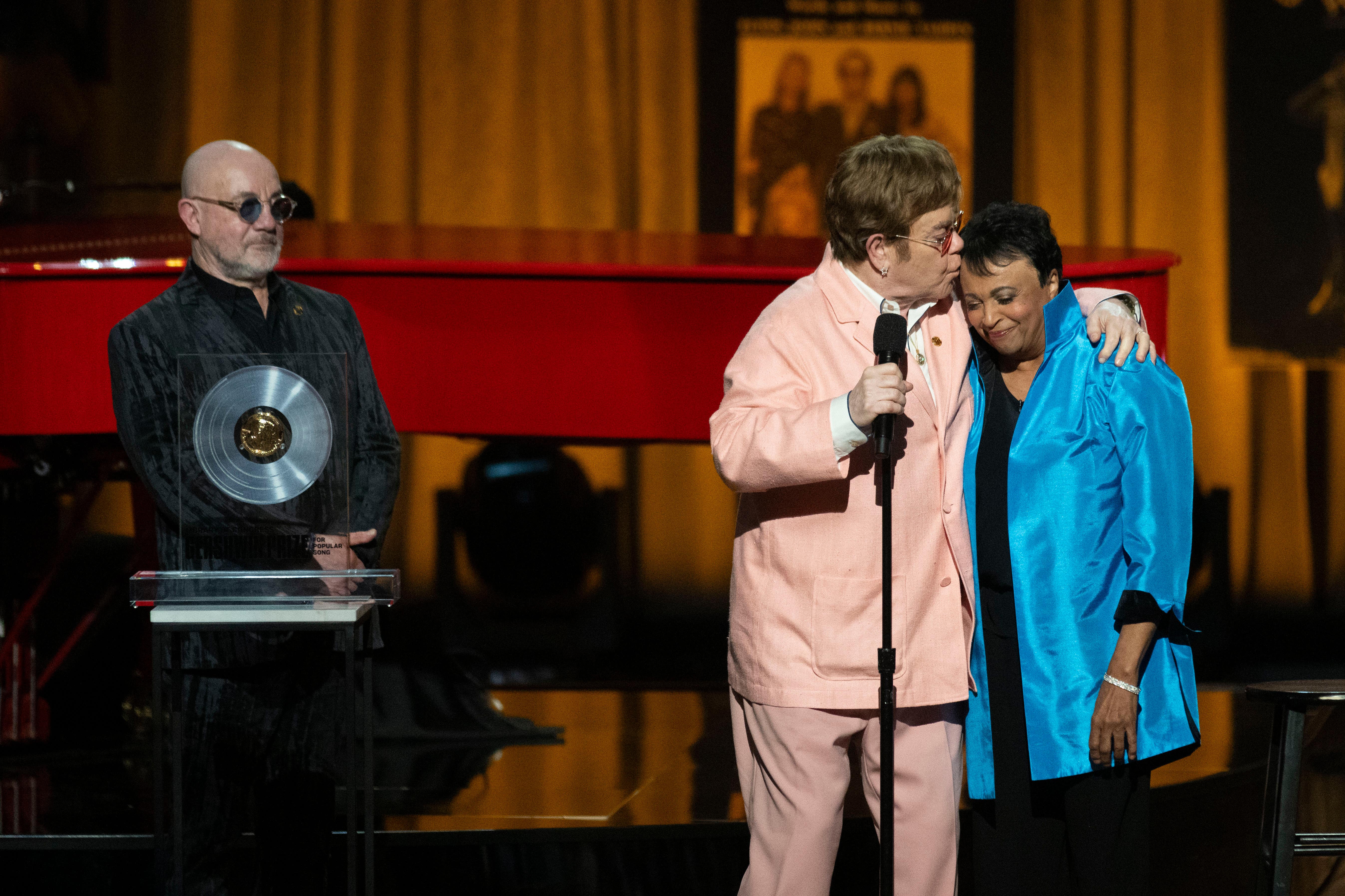 The singer, centre, collected the award together with his songwriting partner Bernie Taupin, left
