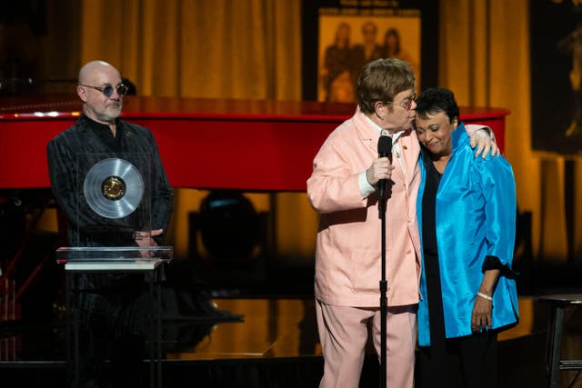 <p>The singer, centre, collected the award together with his songwriting partner Bernie Taupin, left </p>