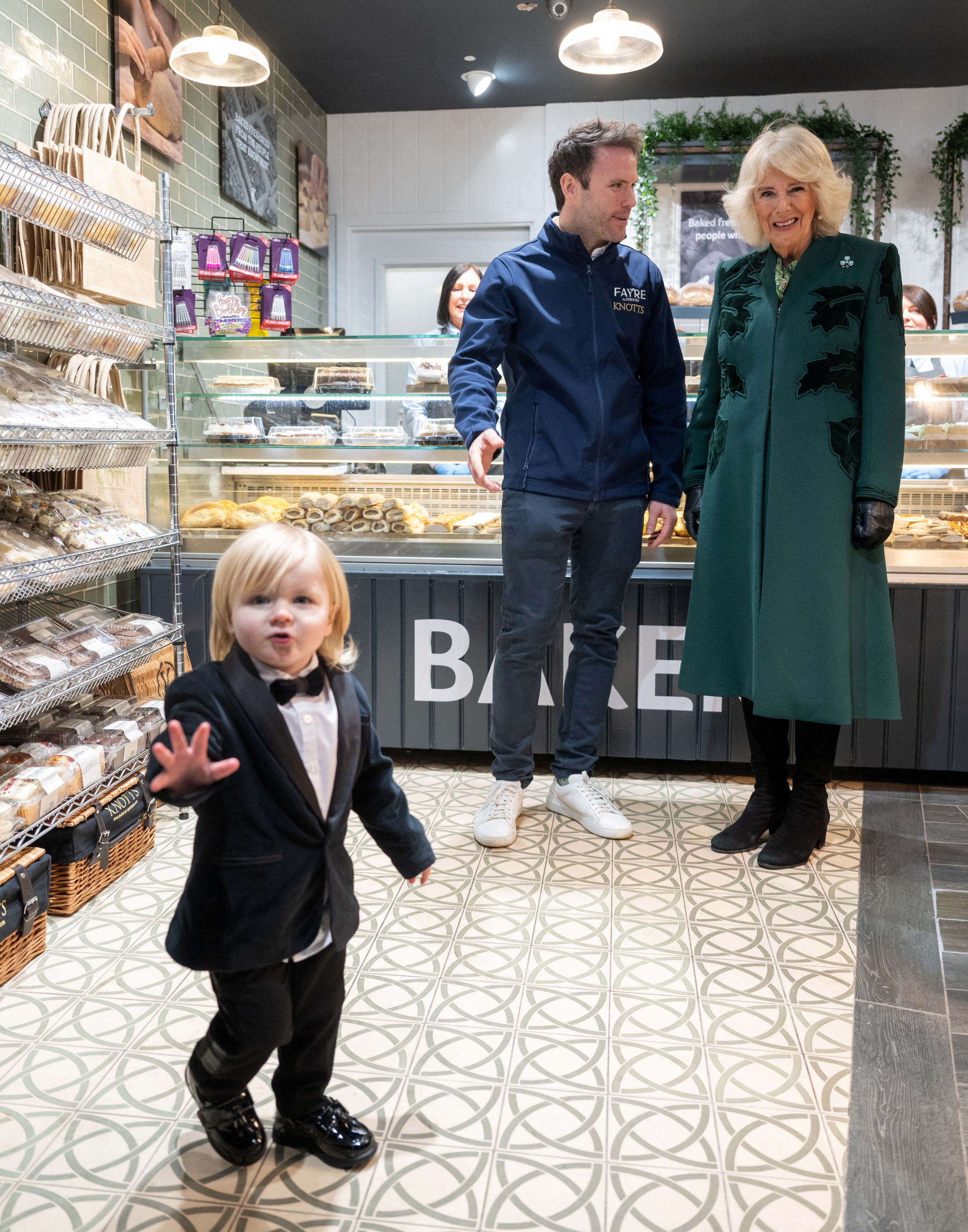 Queen Camilla looks on at Fitz William Salmon-Corrie in Knotts Bakery during her visit to Northern Ireland on Thursday
