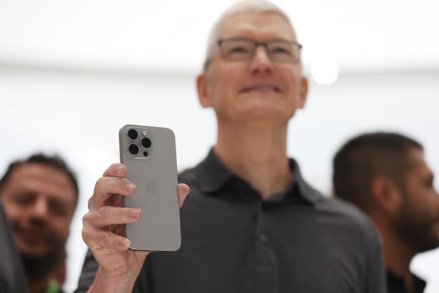 <p>Apple CEO Tim Cook holds up a new iPhone 15 Pro</p>