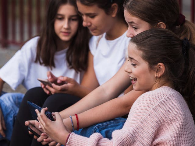 <p>Girls sitting on a school staircase relaxed and using mobile phones.</p>