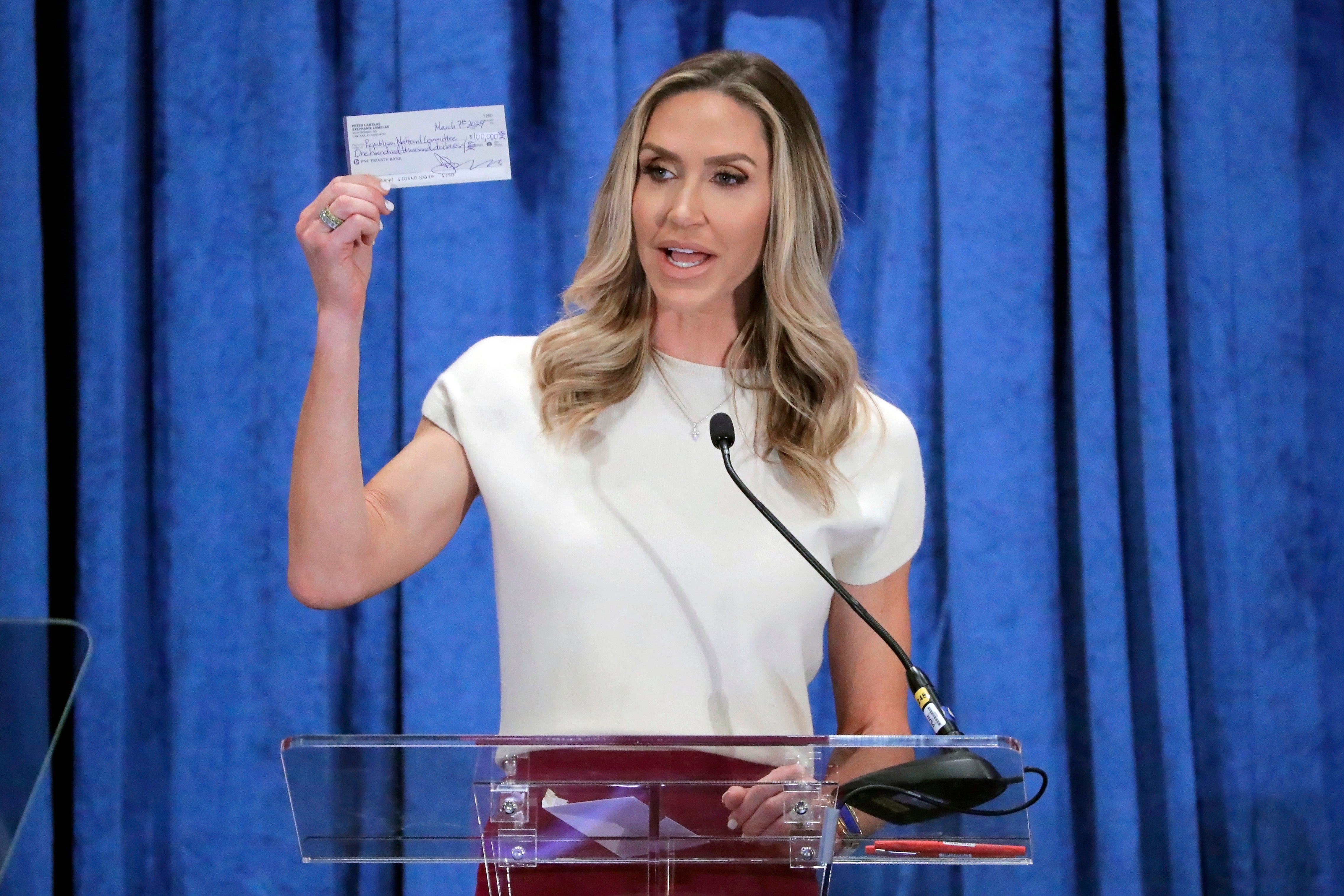 Lara Trump, the newly elected co-chair of the Republican National Committee, holds up a donation check as she gives an address during the general session of the RNC Spring Meeting on 8 March in Houston, Texas.