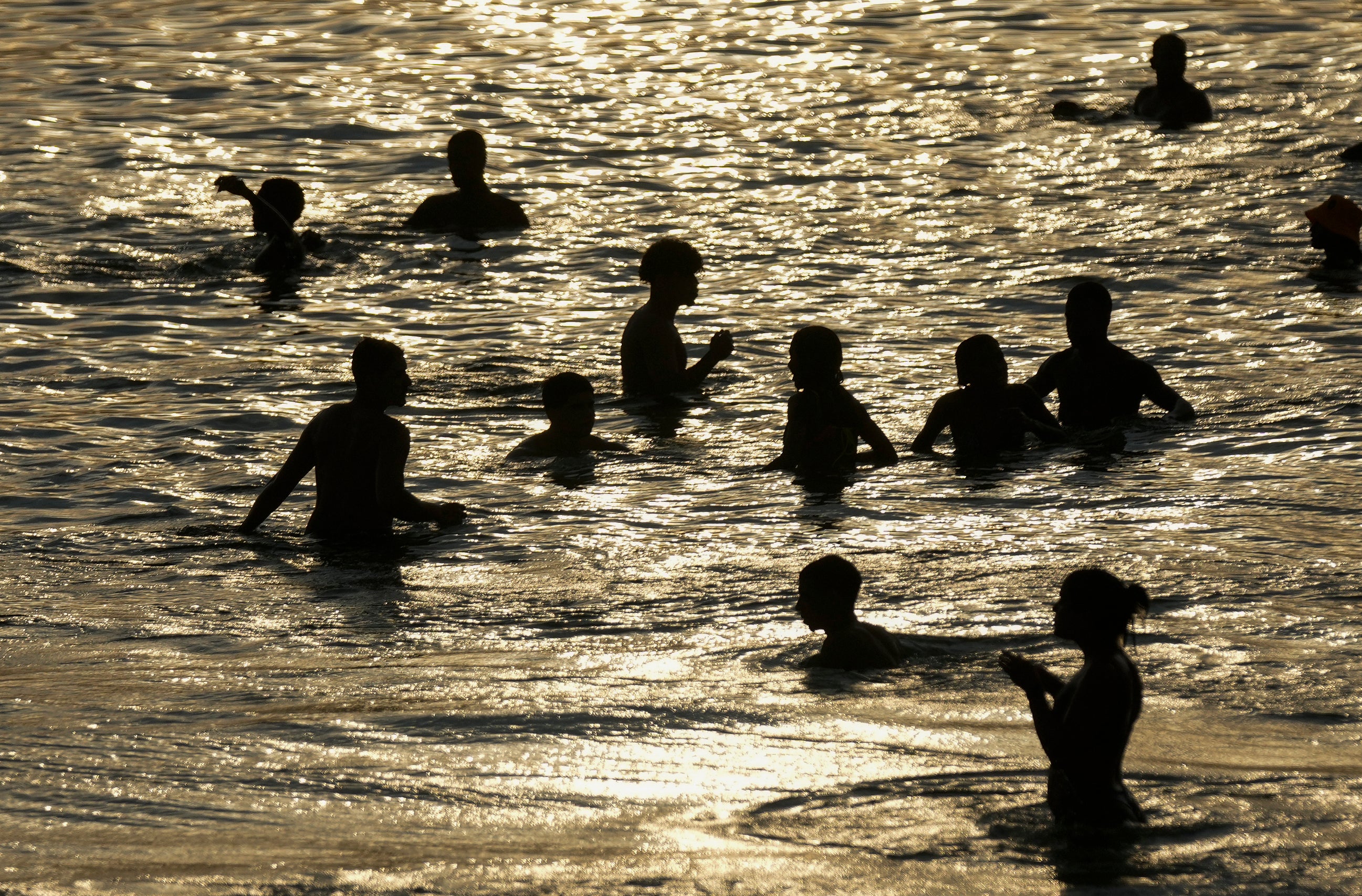 People cool off in the shallow waters of Arpoador beach amid a heat wave, in Rio de Janeiro, Brazil