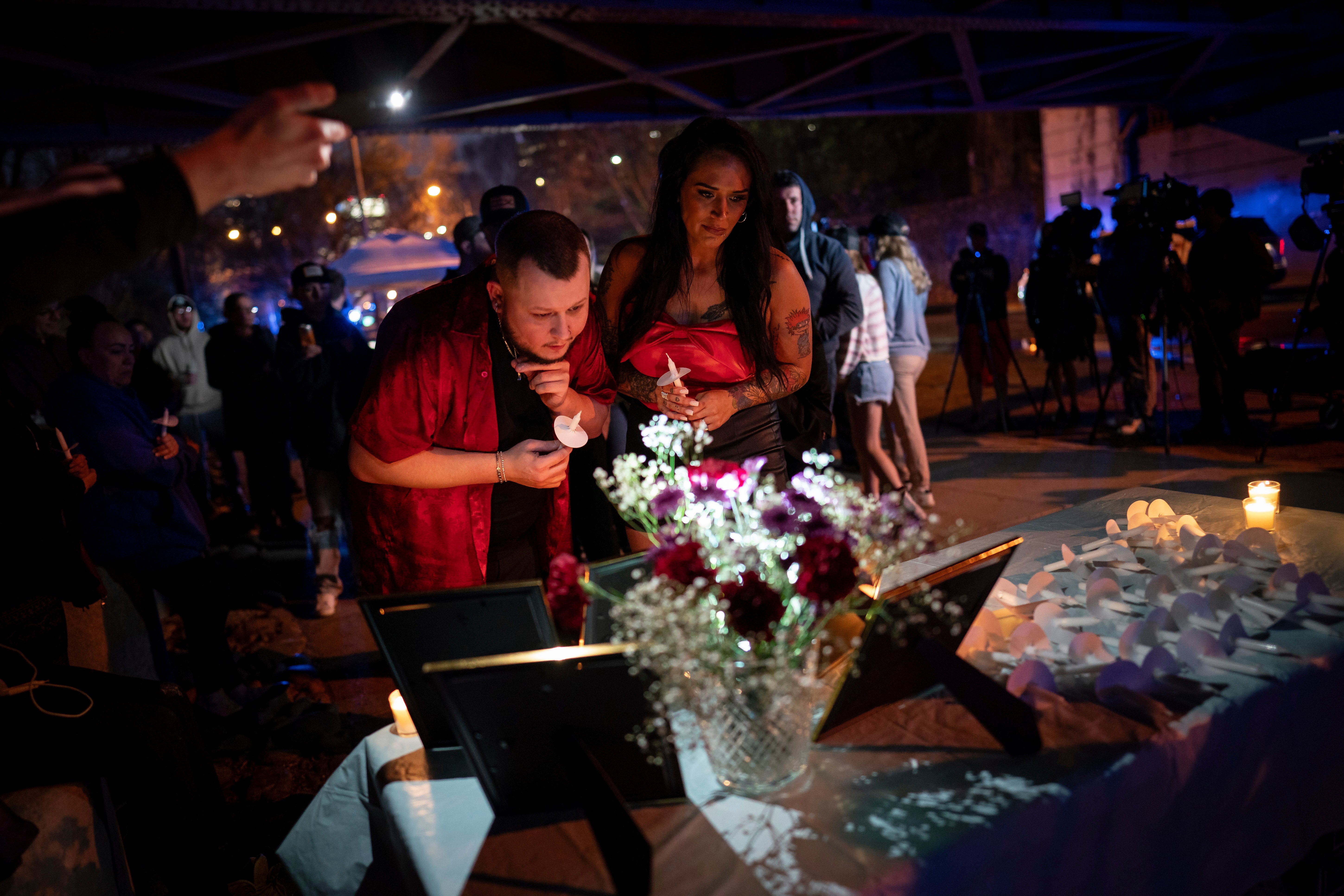 Two attendees look at pictures of Riley Strain during a candlelight vigil on Friday evening