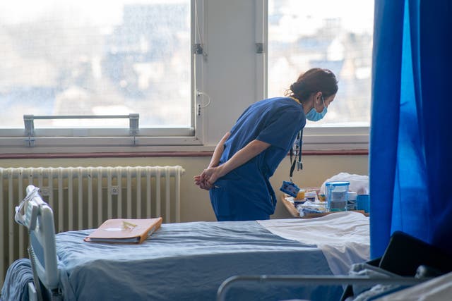 <p>A nurse treating a patient on an NHS ward  </p>