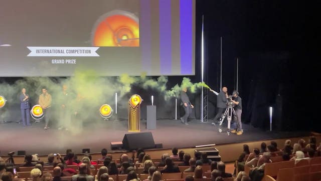 <p>Activist lights flare on stage during TV festival in France.</p>