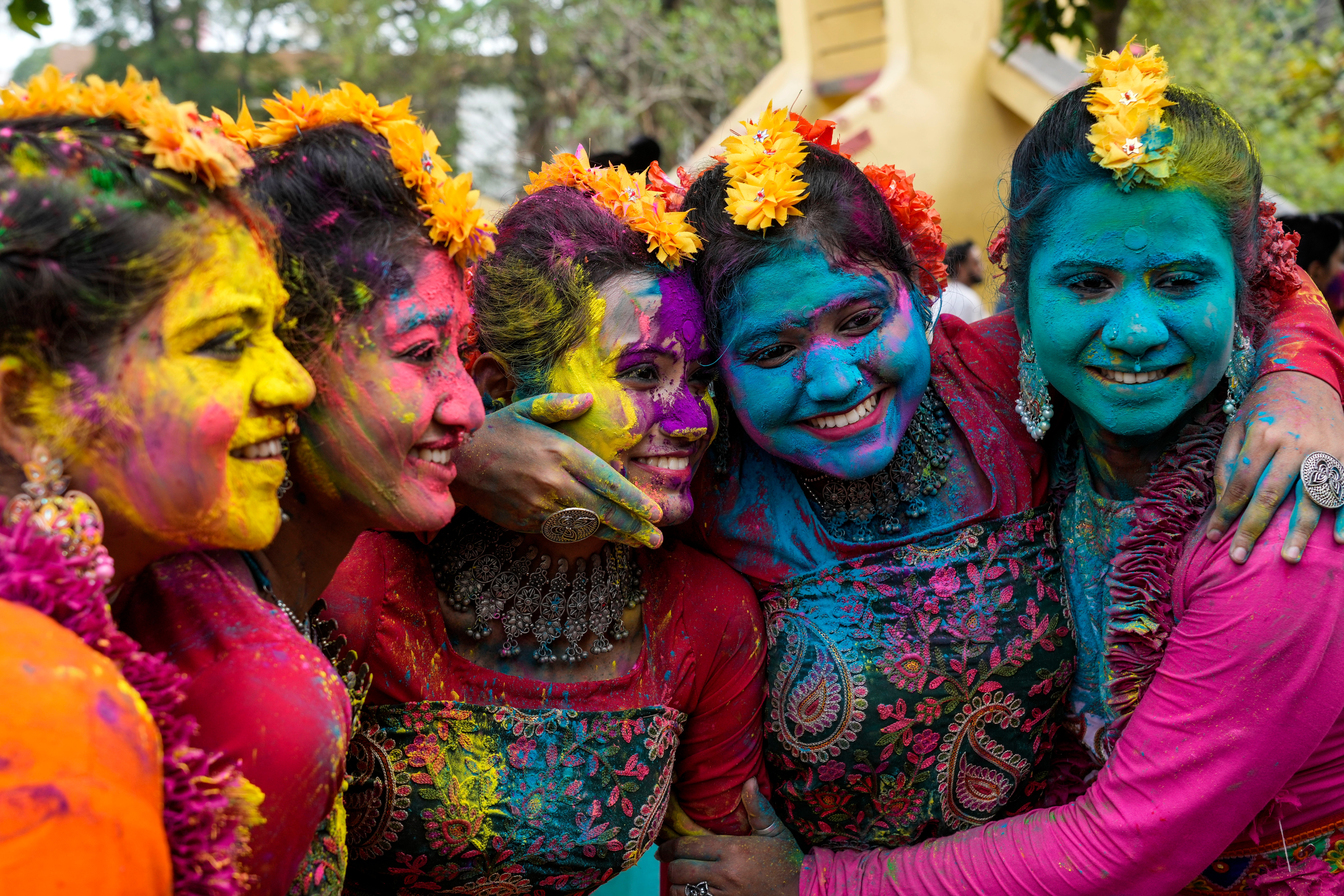 Women, with their faces smeared with coloured powder, pose for a photograph as they celebrate Holi, the festival of colors, in Kolkata, India