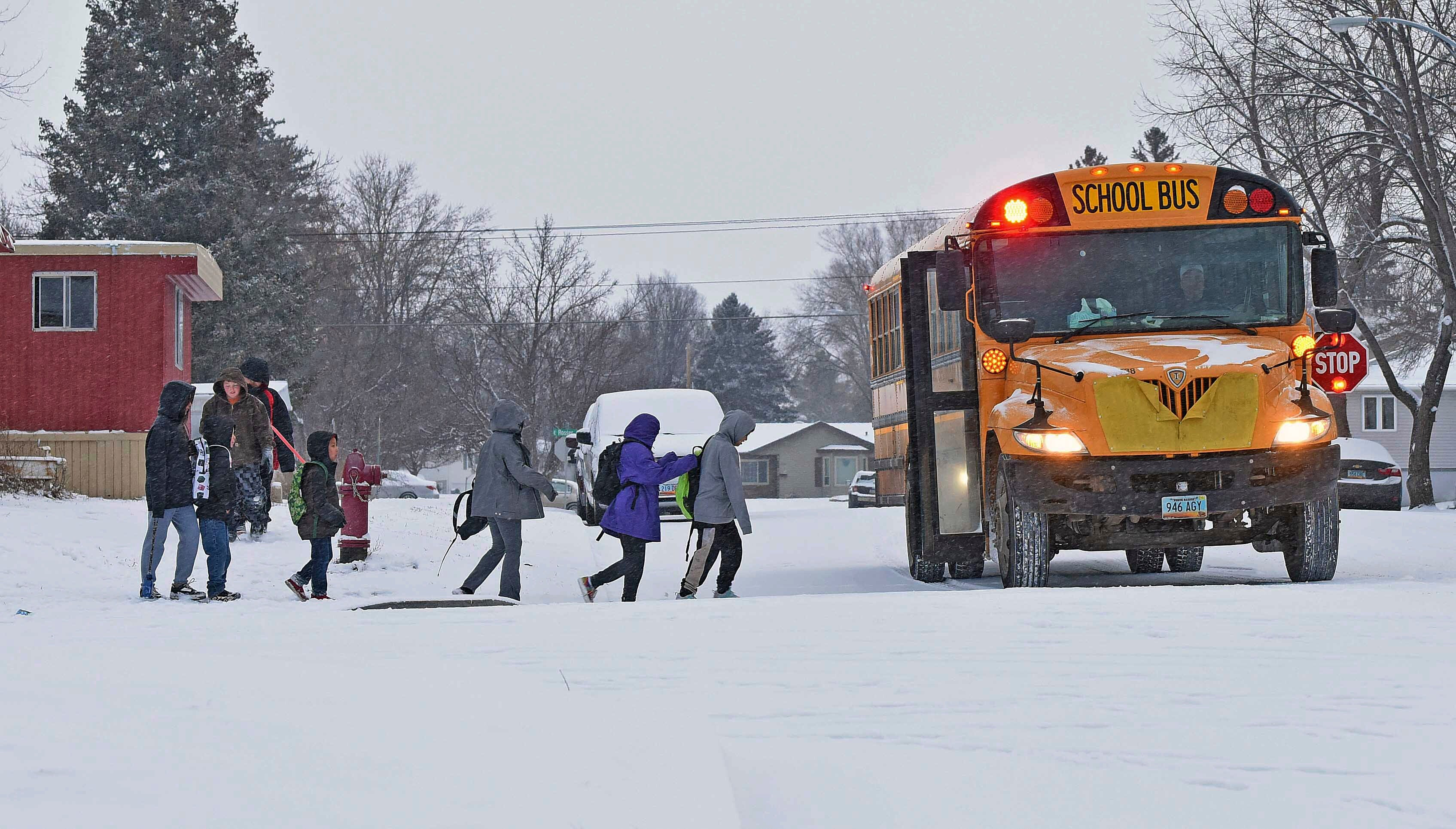 Children in winter coats line up to get into a school bus Thursday, March 21, 2024 in Bismarck, N.D