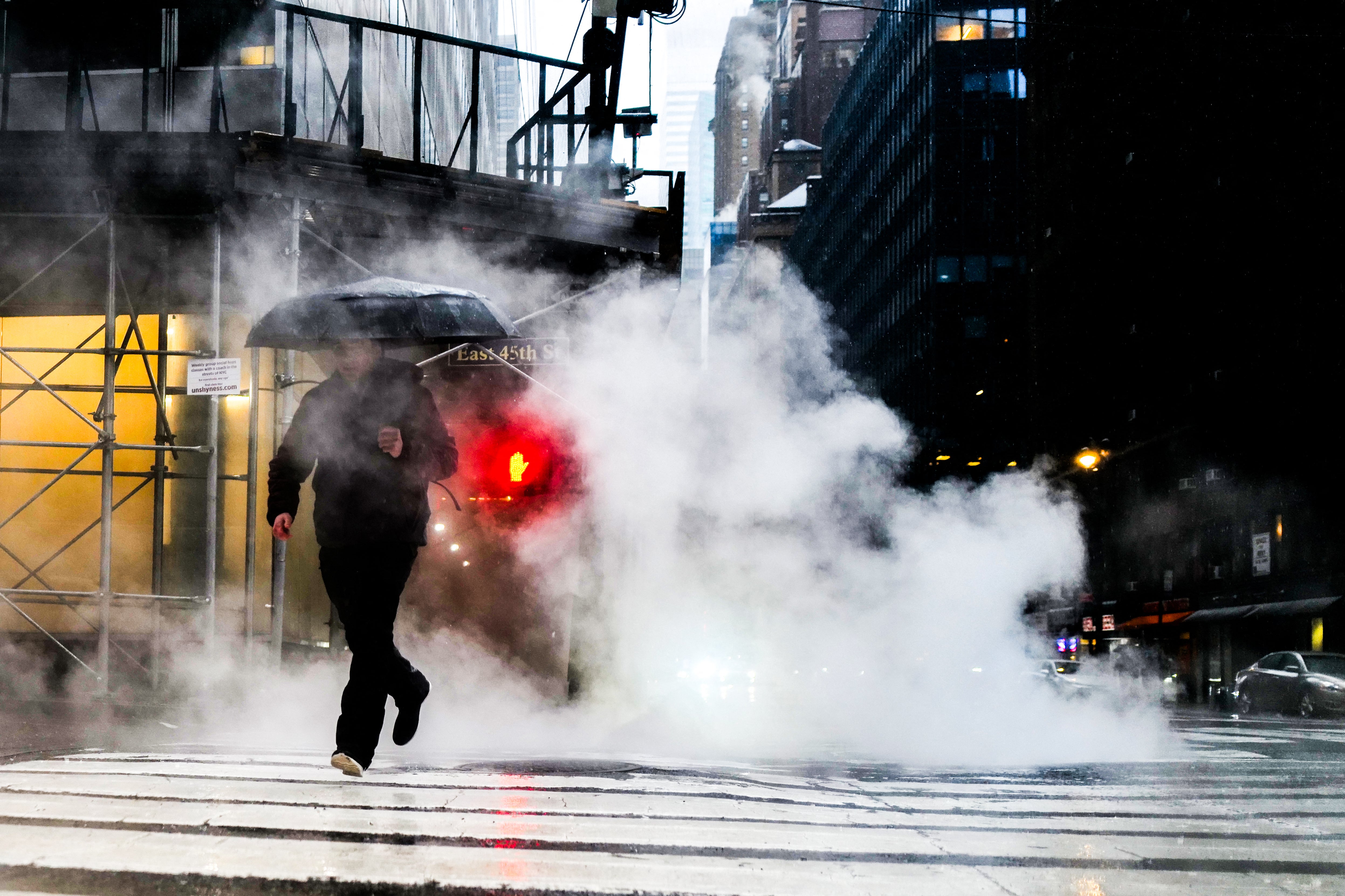 A man crosses a street during heavy rain in the Manhattan borough of New York on March 23