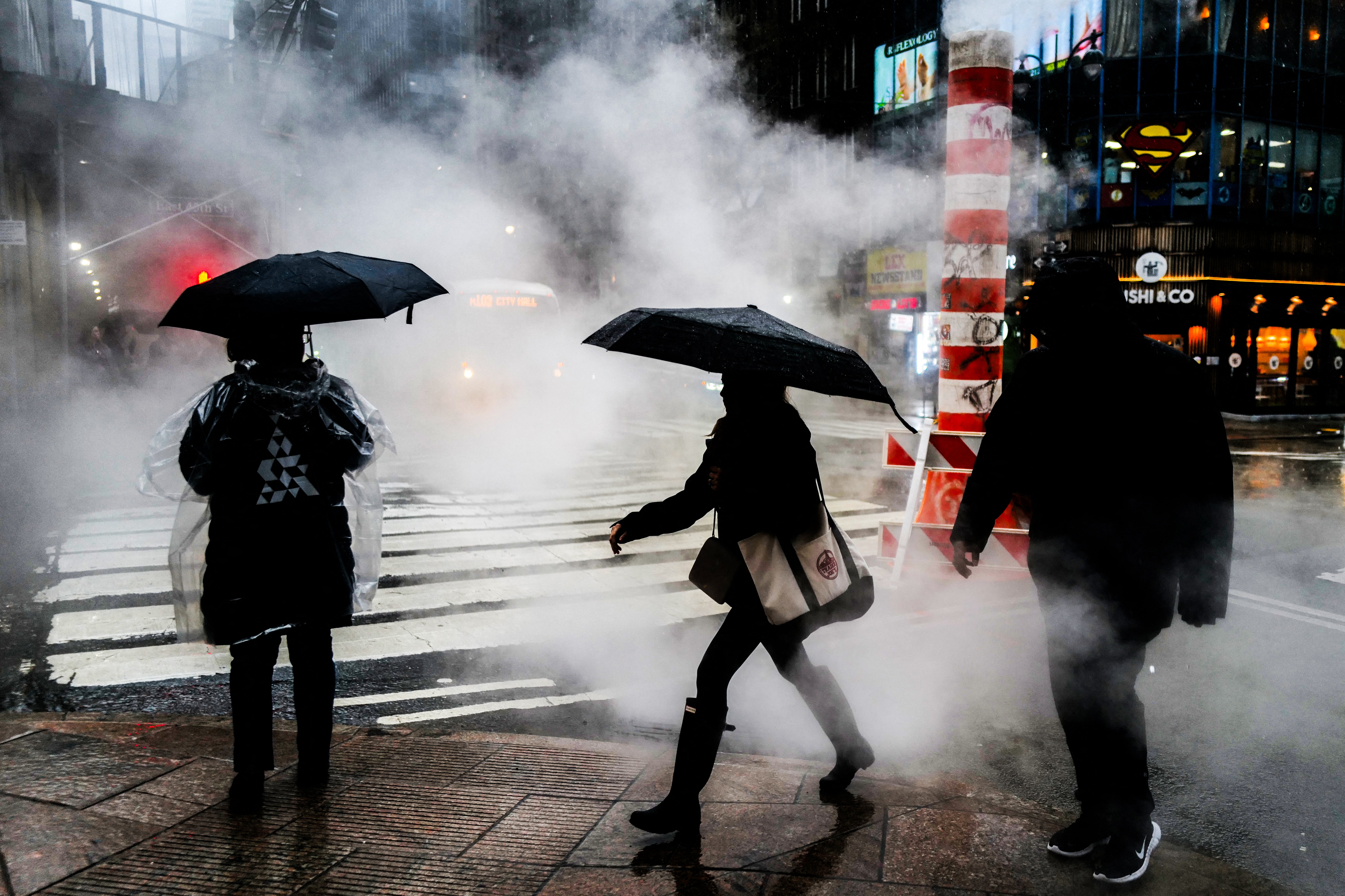People walk in the street during heavy rain in the Manhattan borough of New York on March 23