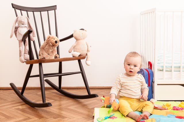 <p>A nursery with a rocking chair, crib and baby. </p>