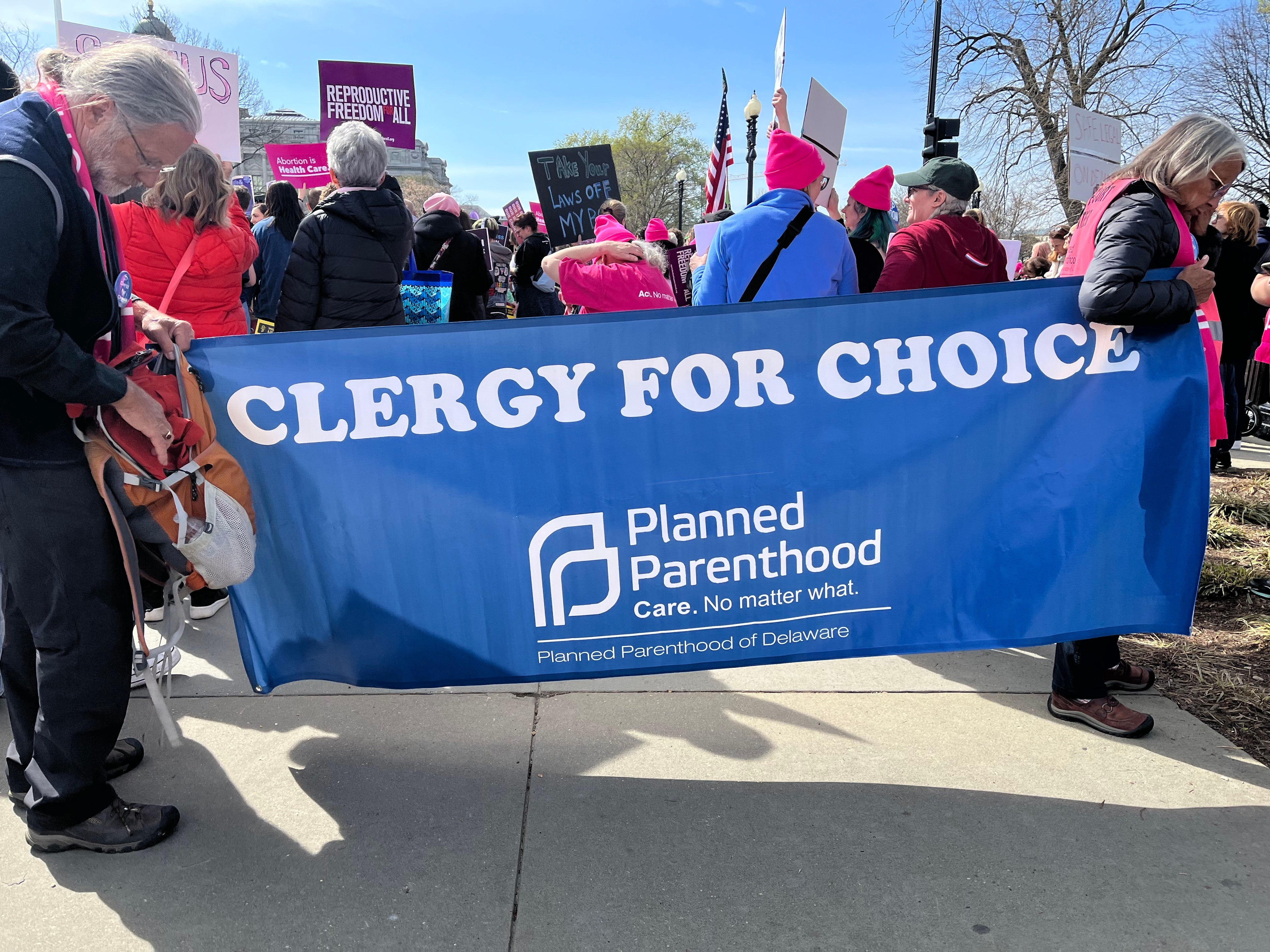 Two demonstrators hold a banner that reads, “Clergy for Choice."