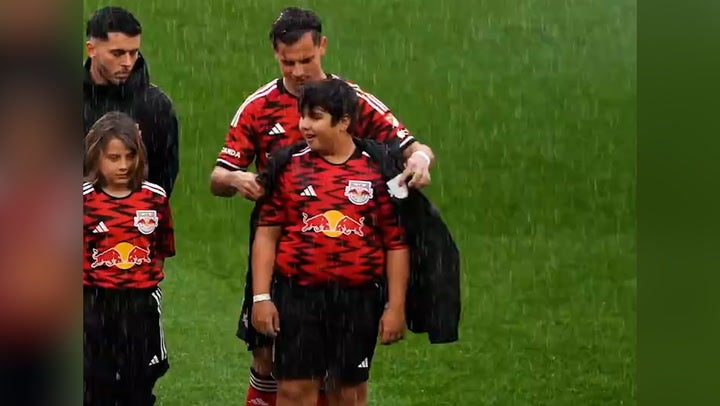 <p>New York Red Bulls give coats to young mascots during torrential rain.</p>