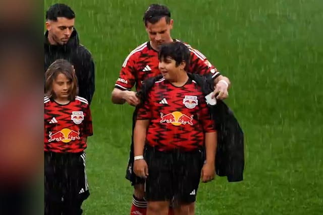 <p>New York Red Bulls give coats to young mascots during torrential rain.</p>