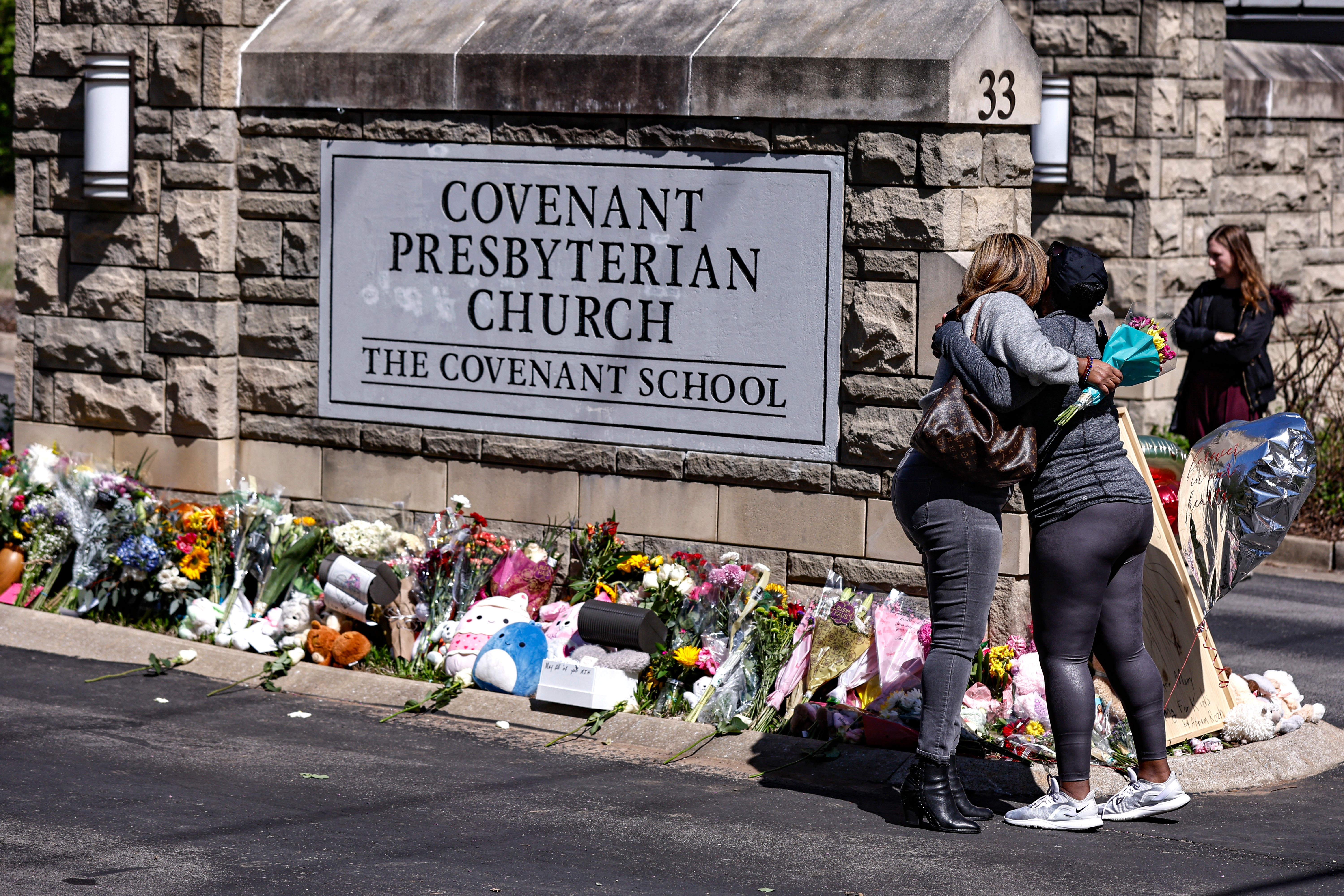 Two women hug near a memorial at the entrance to The Covenant School, March 29, 2023, in Nashville, Tennessee