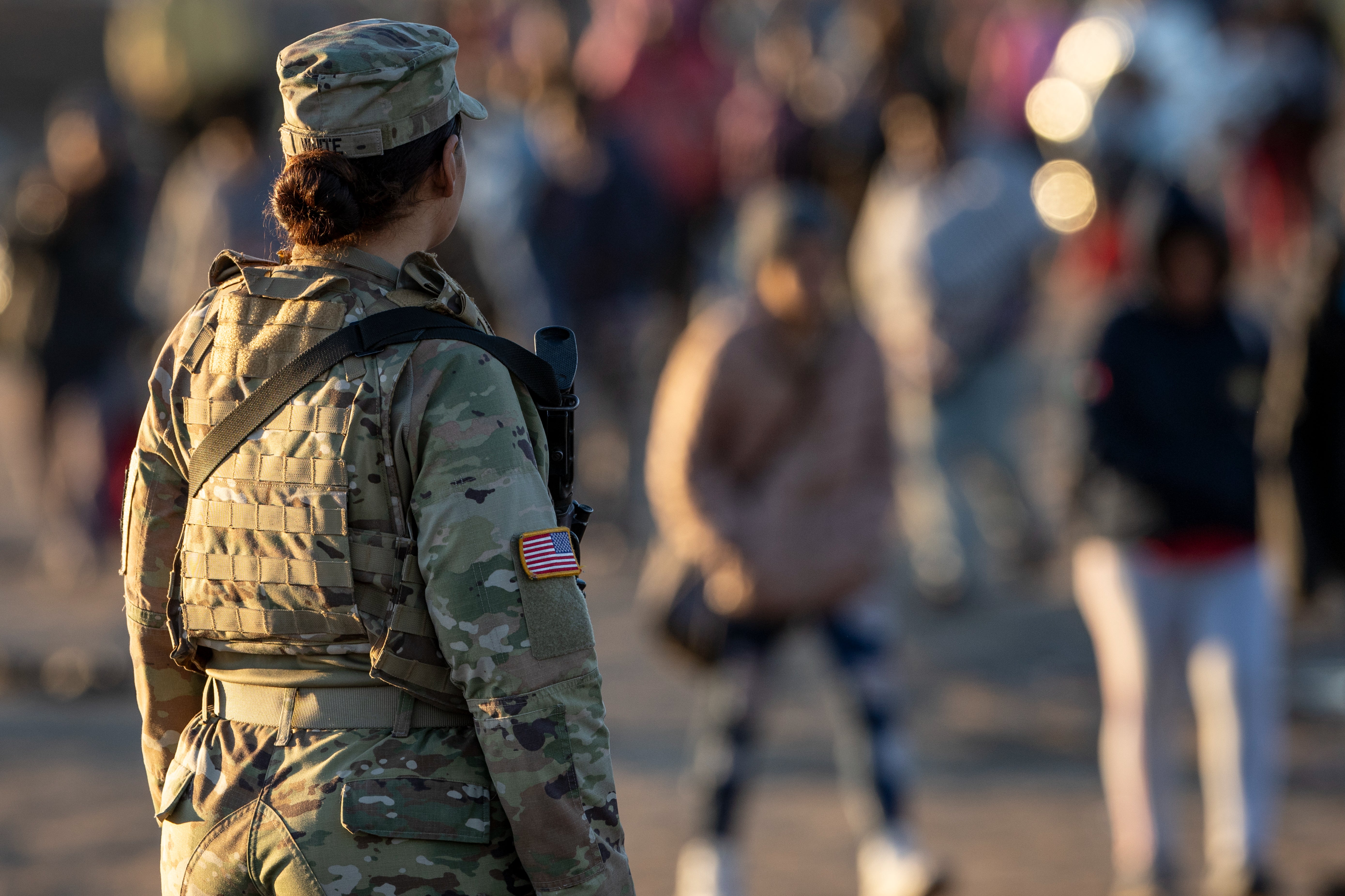 A Texas National Guard soldier observes as thousands of immigrants walk towards a U.S. Border Patrol transit center on December 19, 2023