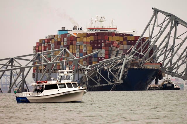 <p>A small boat is anchored in front of a cargo ship that is stuck under the part of the structure of the Francis Scott Key Bridge after the ship hit the bridge Wednesday, March 27, 2024, in Baltimore, Md</p>