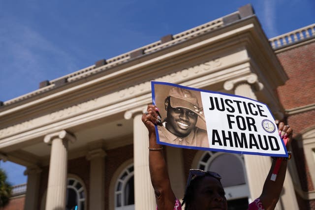 <p>A demonstrator holds a sign that reads, ‘Justice for Ahmaud’ after three men murdered him while he was on a jog in their neighbourhood</p>
