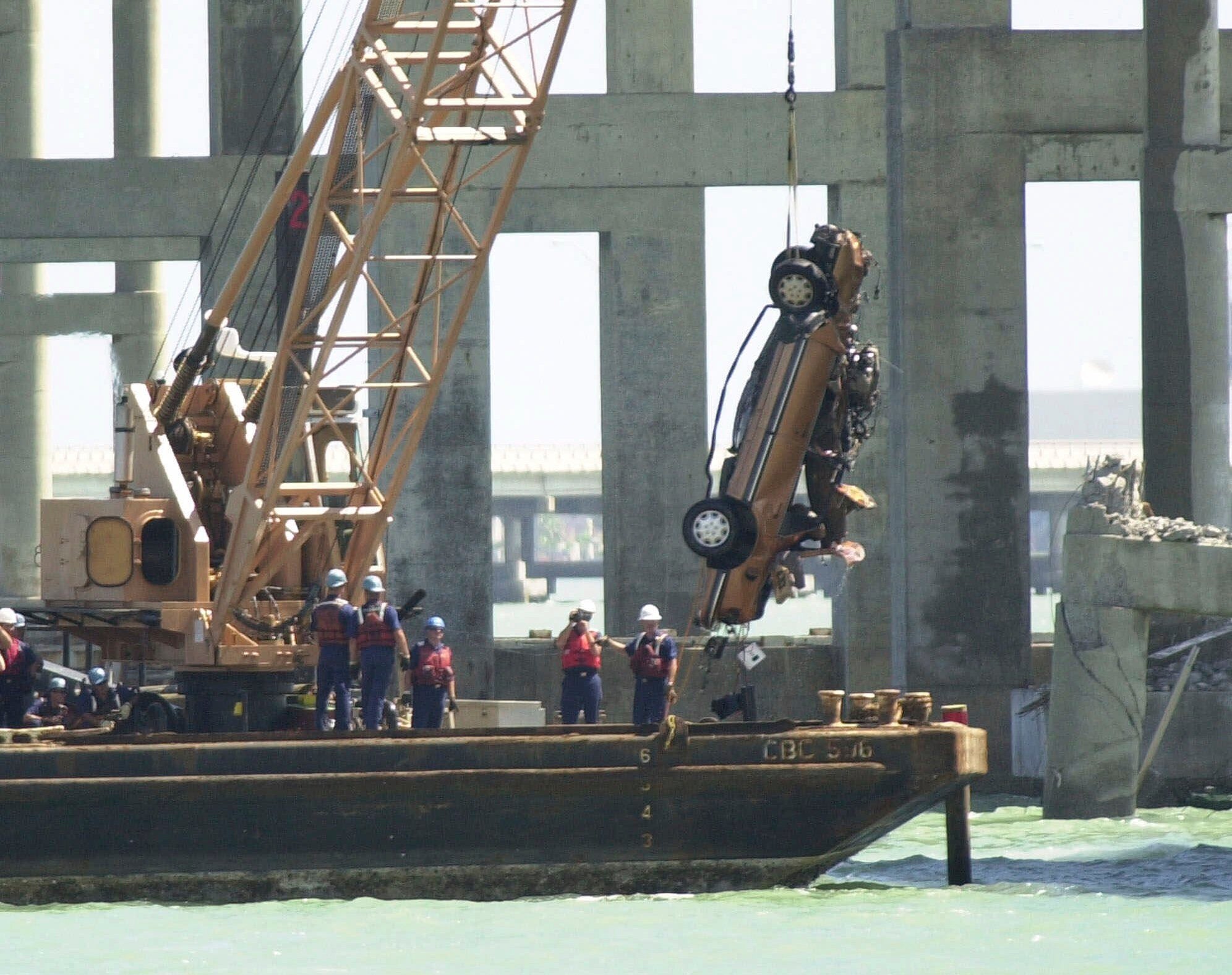 FILE - Recovery workers pull a car from the bay at the site where the Queen Isabella Causeway collapsed, in Port Isabel