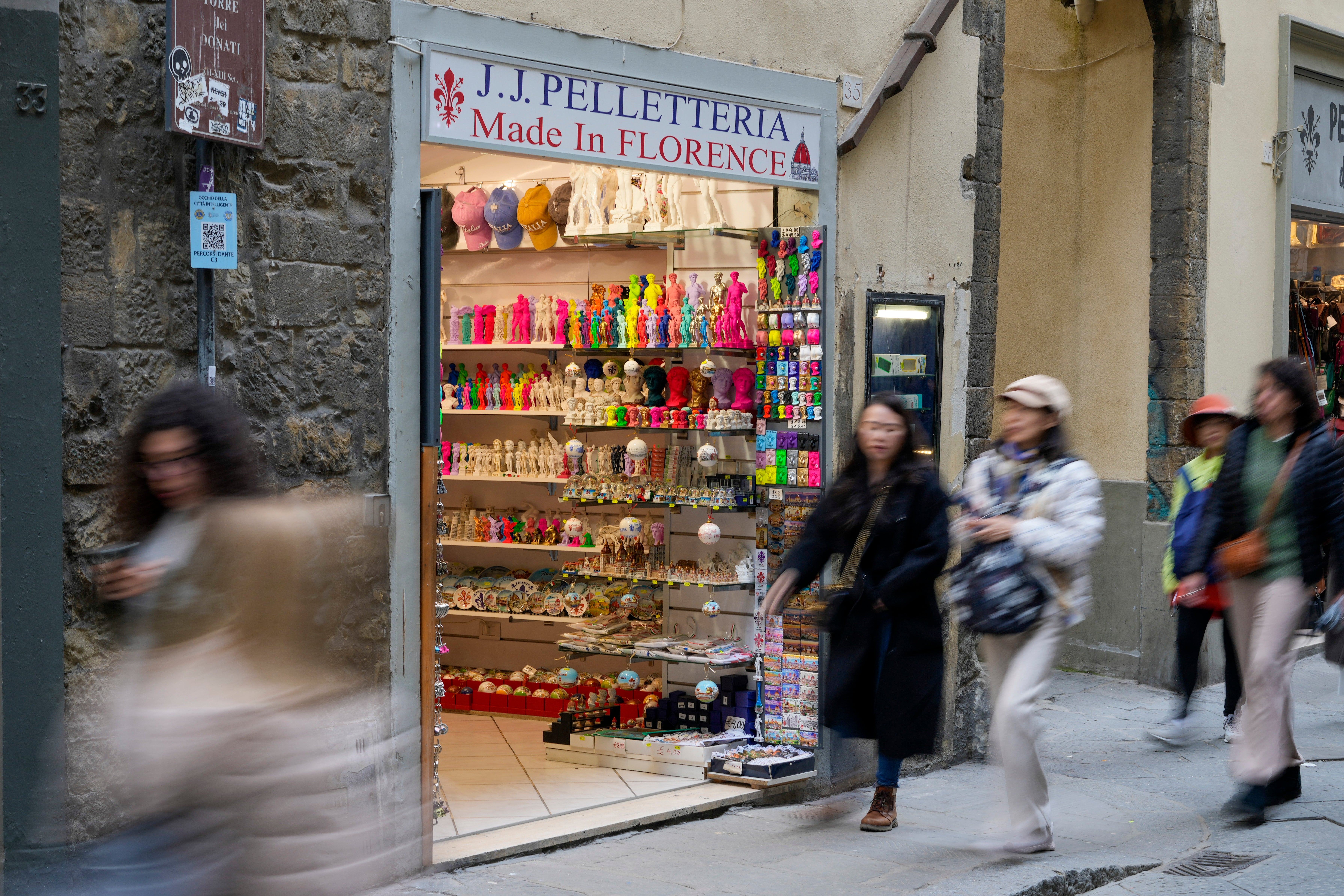 People walk past a shop selling souvenirs of Michelangelo’s David in downtown Florence