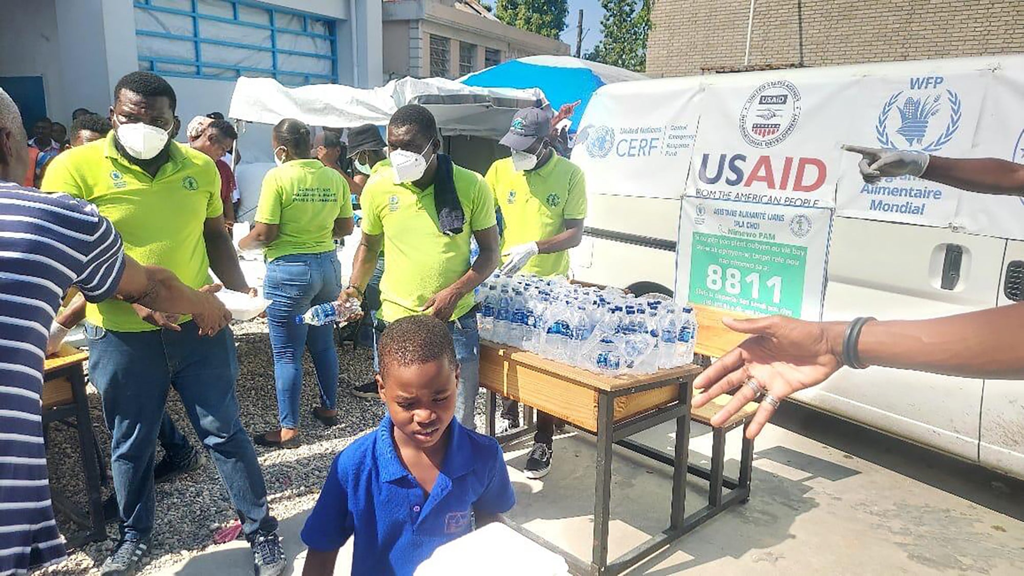 Ignace, aged six, receives hot meals and water provided by the WFP and a local partner at a site in Port-au-Prince