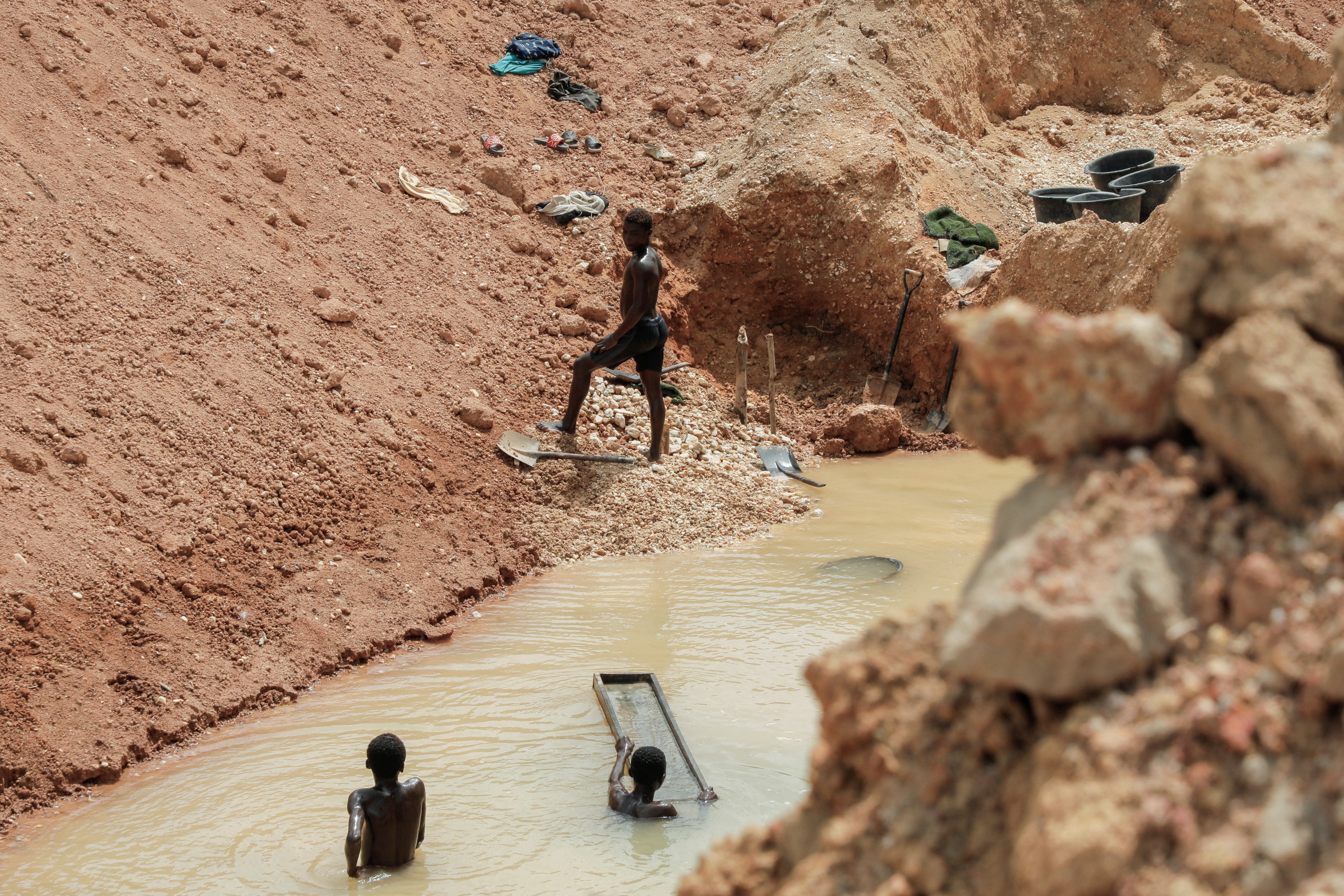 Young boys mine for gold at a mining-ravaged cocoa plantation in the Western region