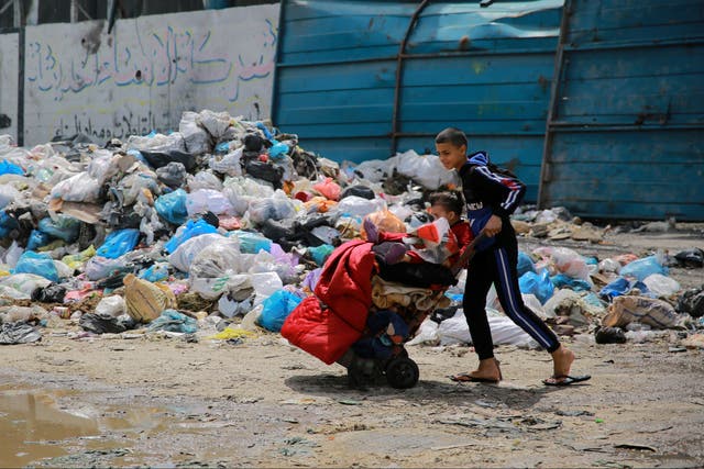 <p>A child walks through Gaza City with belongings</p>